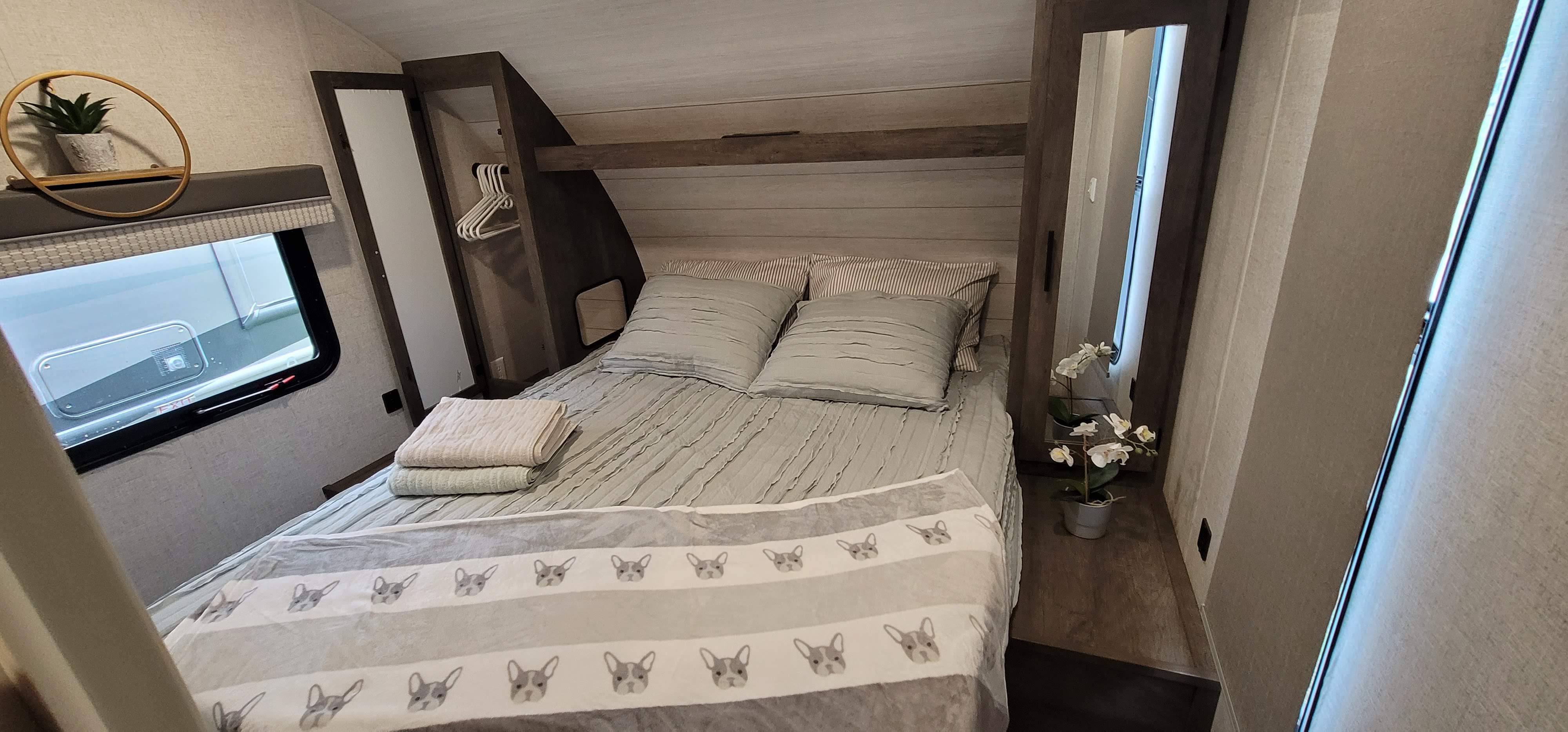 Experience comfort in this RV rental bedroom. It features a cozy bed, window, closet, and a fun dog-patterned blanket.. Forest River Salem Cruise Lite 2021