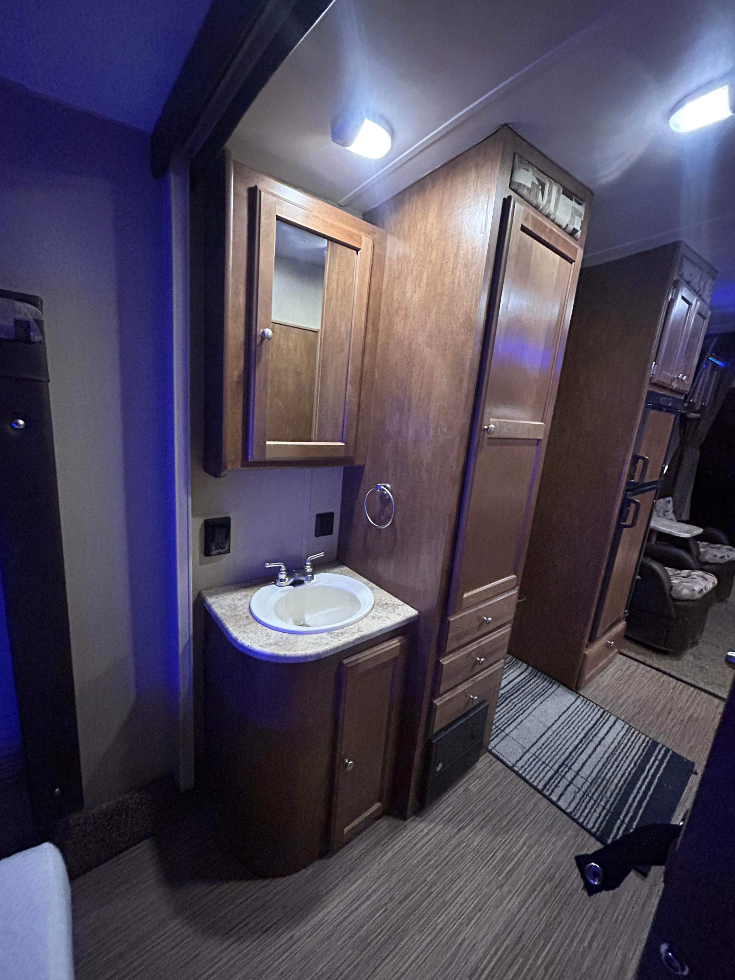 Inside an RV rental, a compact bathroom vanity with sink and mirror, adjacent to storage cabinets and a cozy living area.. Weekend Warrior 2600fs 2017