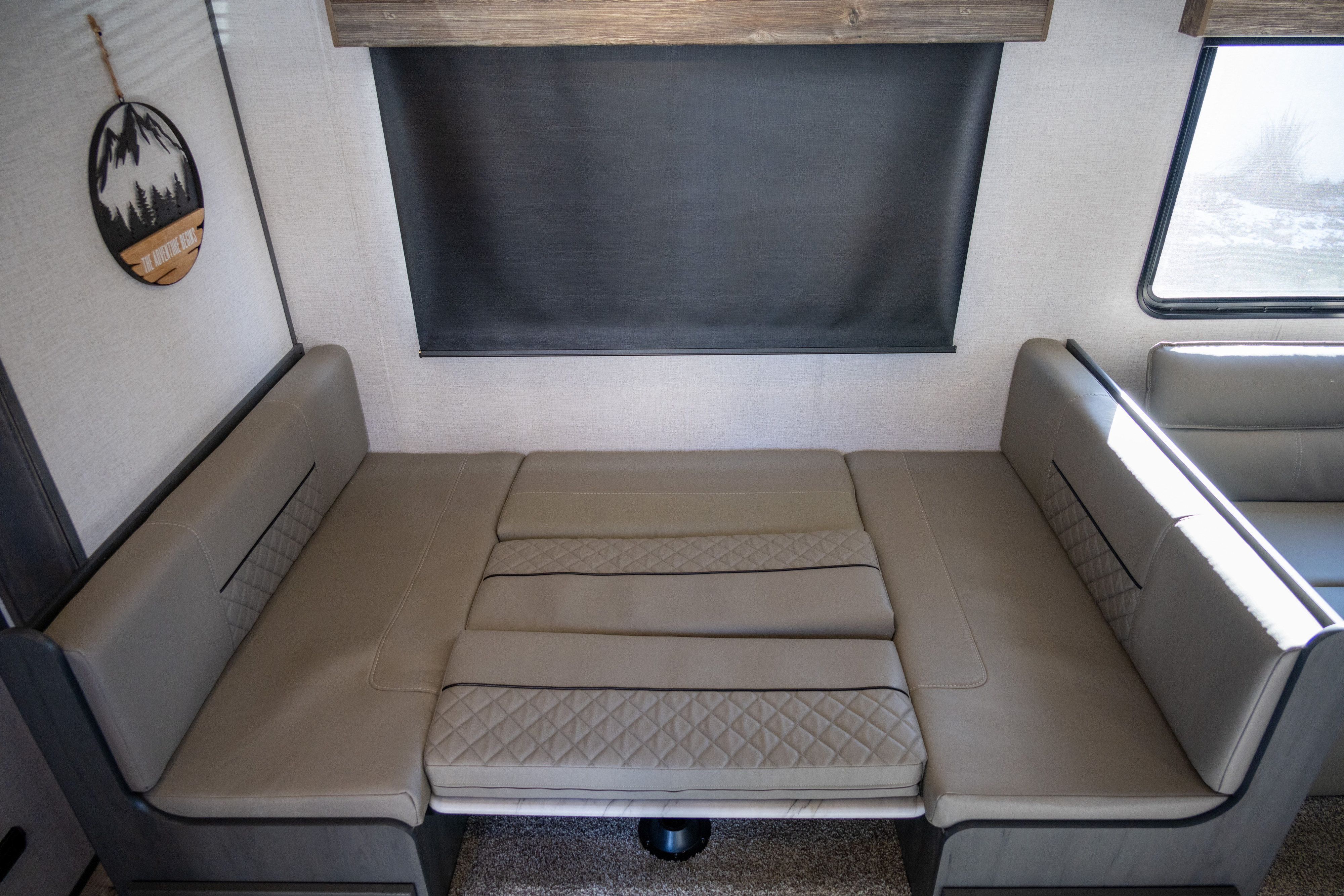 Spacious RV rental dinette area with cozy U-shaped seating, quilted tan cushions, ready for meals or conversion to a bed.. Aspen Trail Aspen Trail Trailer 2022