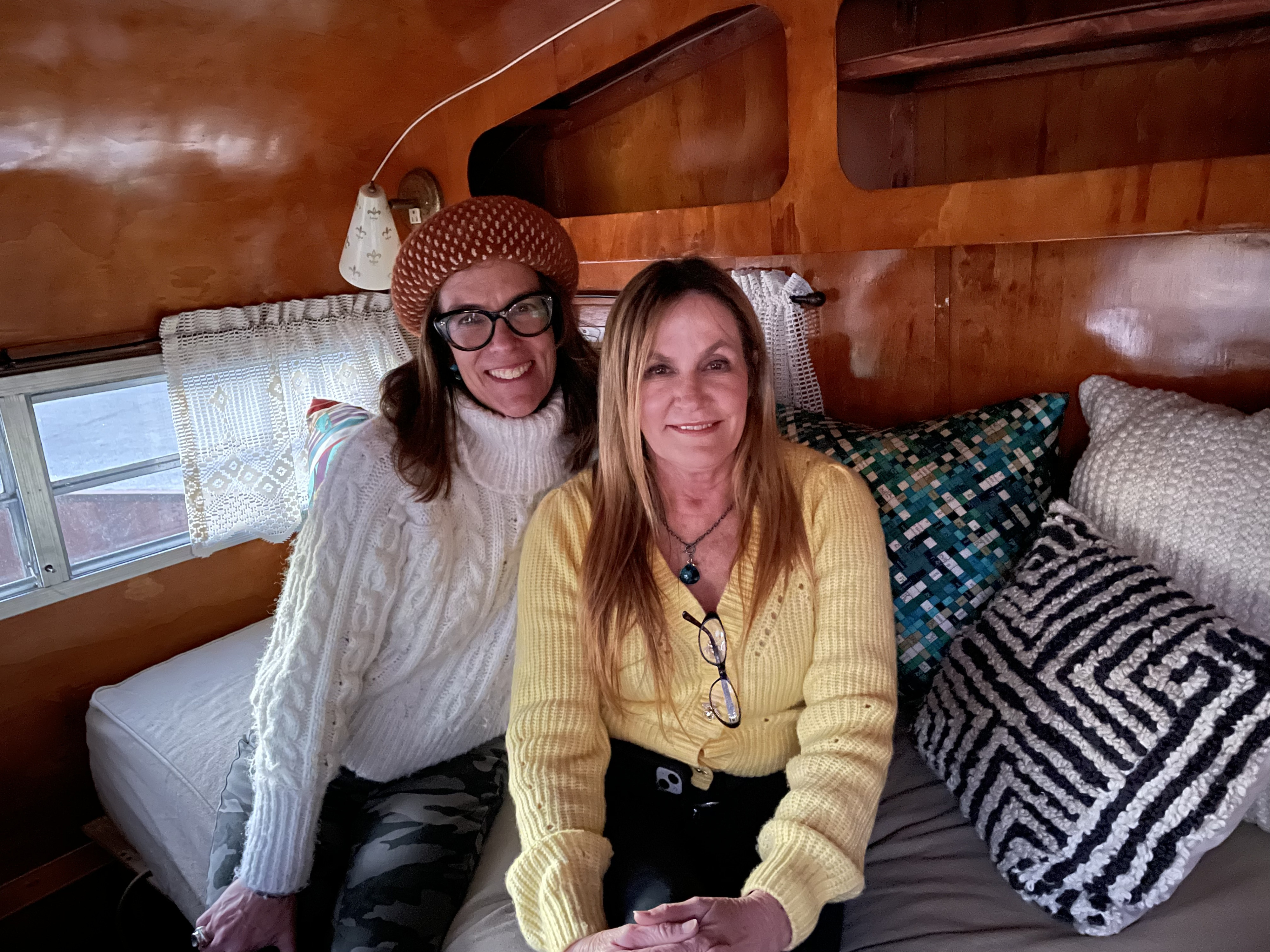 Two smiling women enjoying their cozy RV rental interior, perfect for travel adventures.. Play-Mor Other 1978