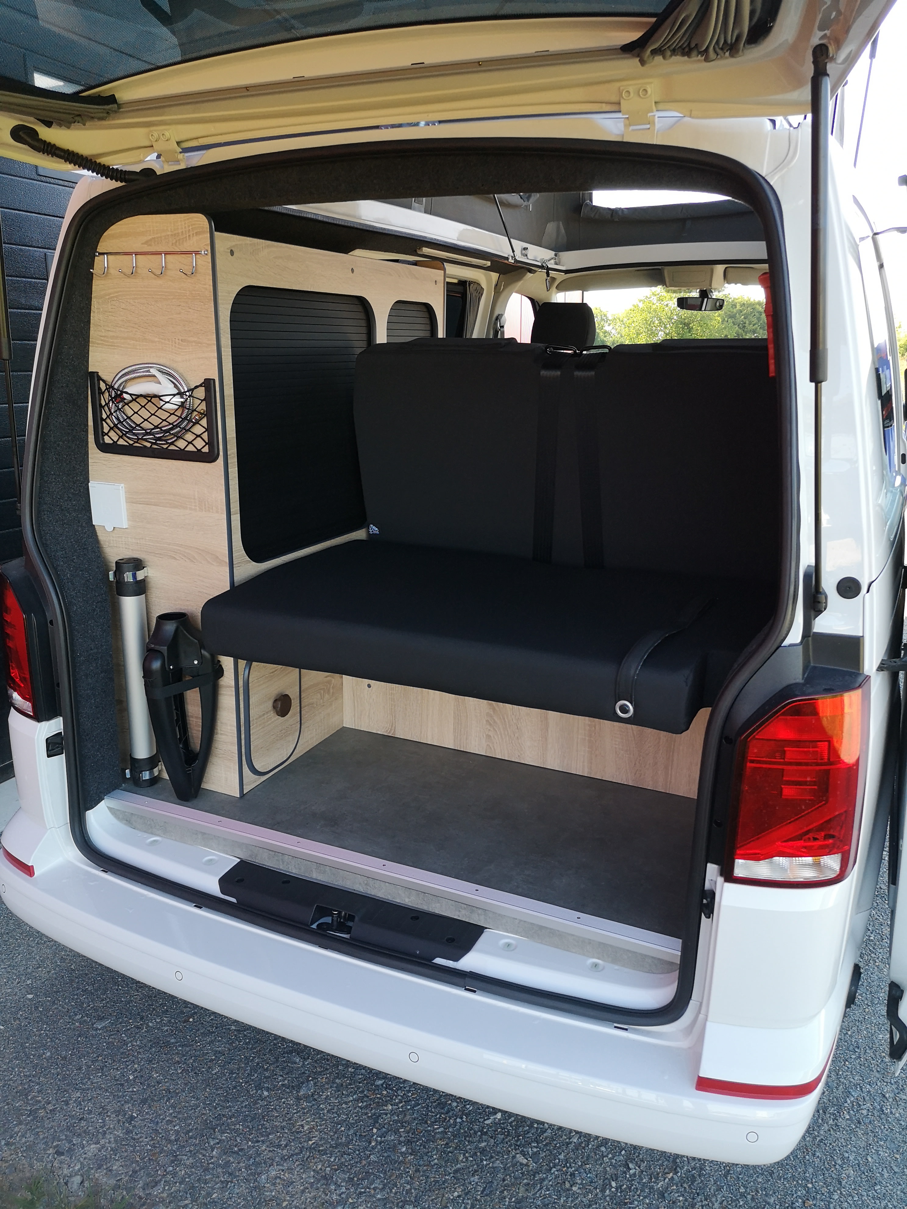 Inside a bright white camper van, ready for your RV rental. Features a convertible bed, wood paneling, and smart storage solutions.. Volkswagen Globe Trotteur 2024