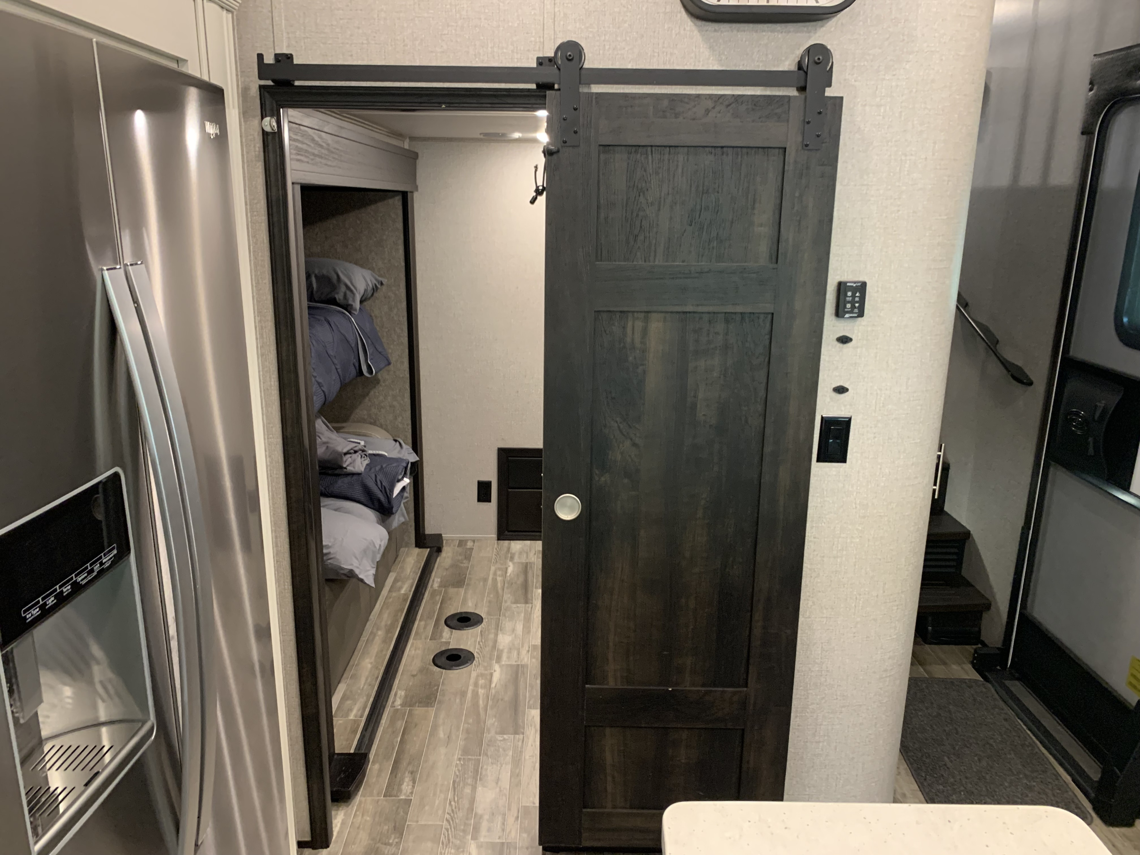 RV rental: Sleek stainless steel fridge, dark wood barn door open to bunk beds. Modern interior layout.. Jayco North Point 2021