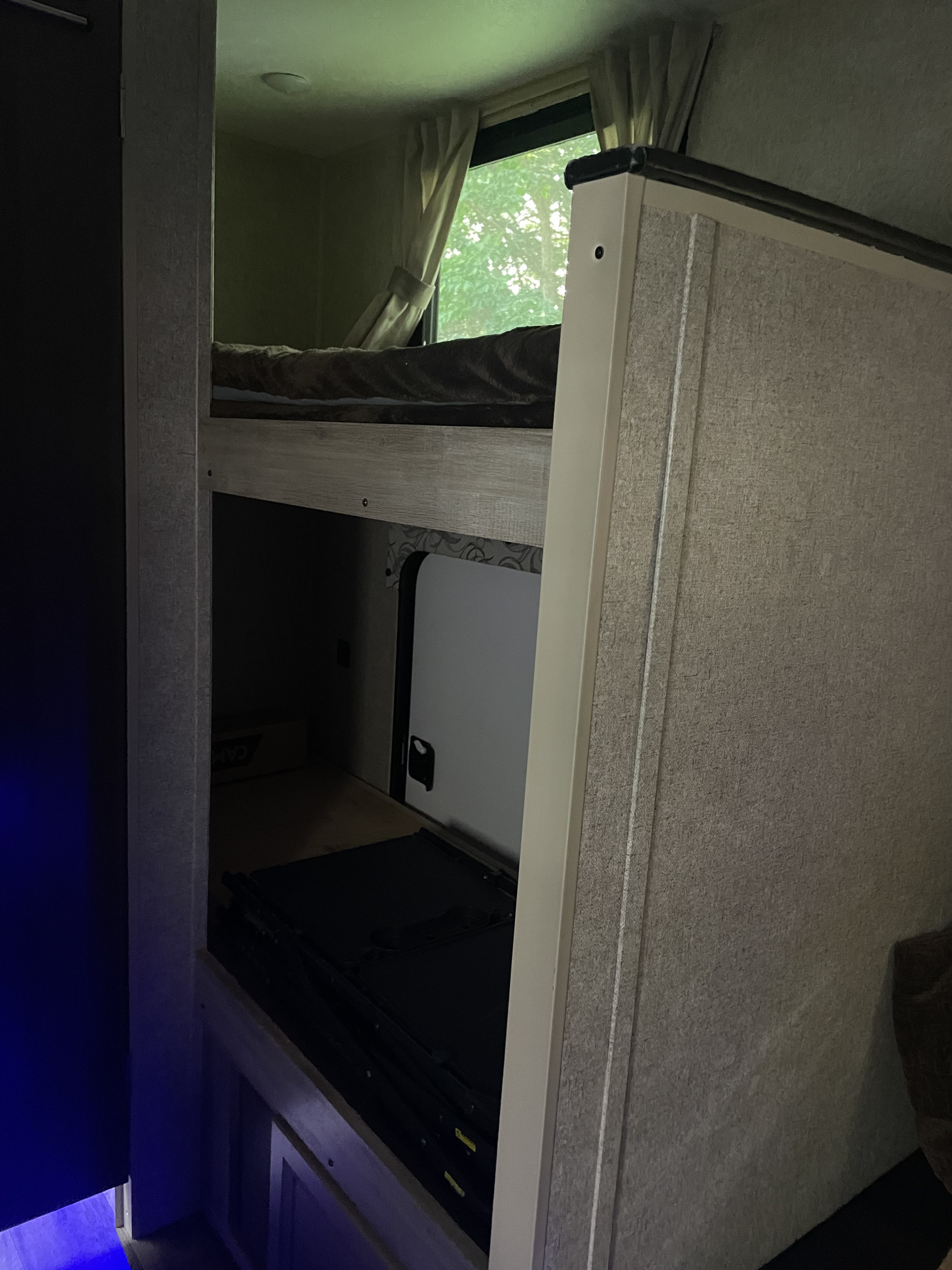 RV rental interior: Showing cozy bunk beds with bedding, a lower storage area with external access, and a window.. Coachmen Catalina Summit 2020