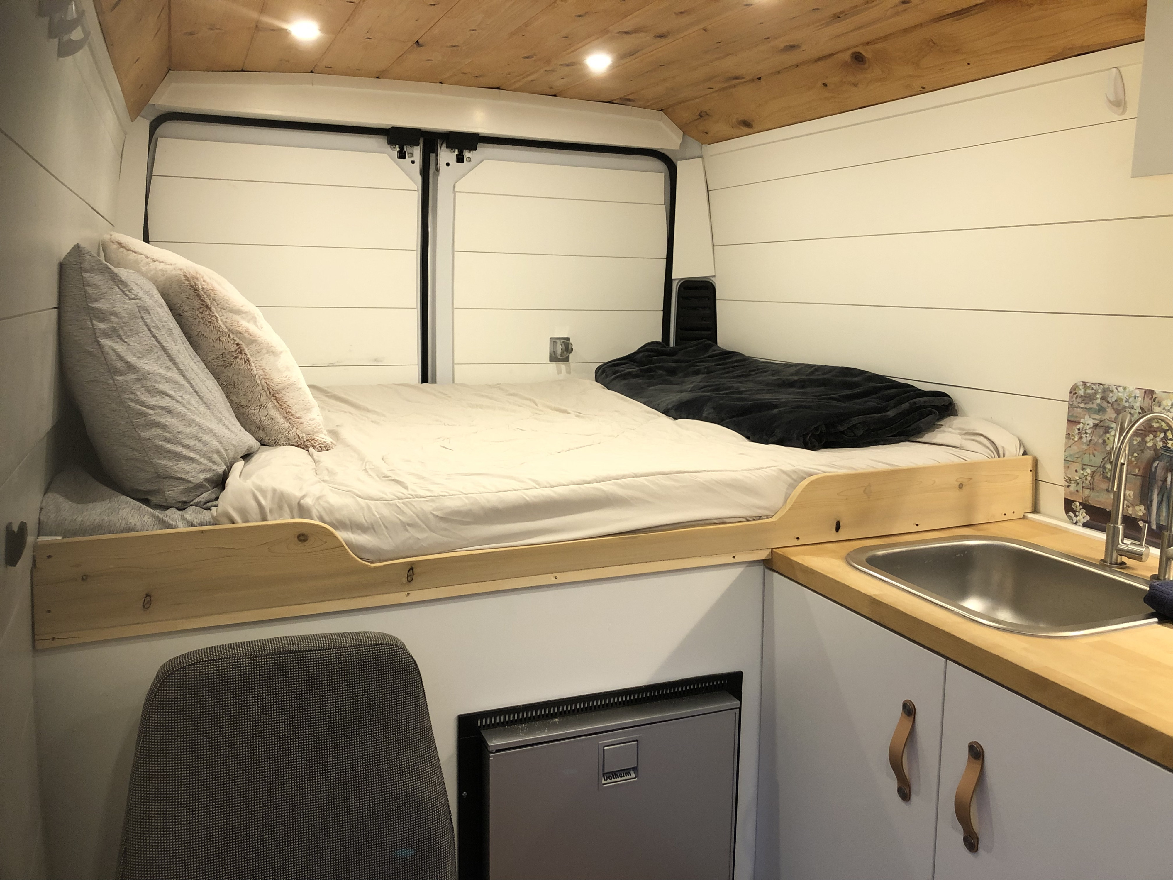 Experience comfort in this RV rental van conversion, featuring a bed, kitchen sink, and compact fridge.. Dodge Promaster 2500 2021