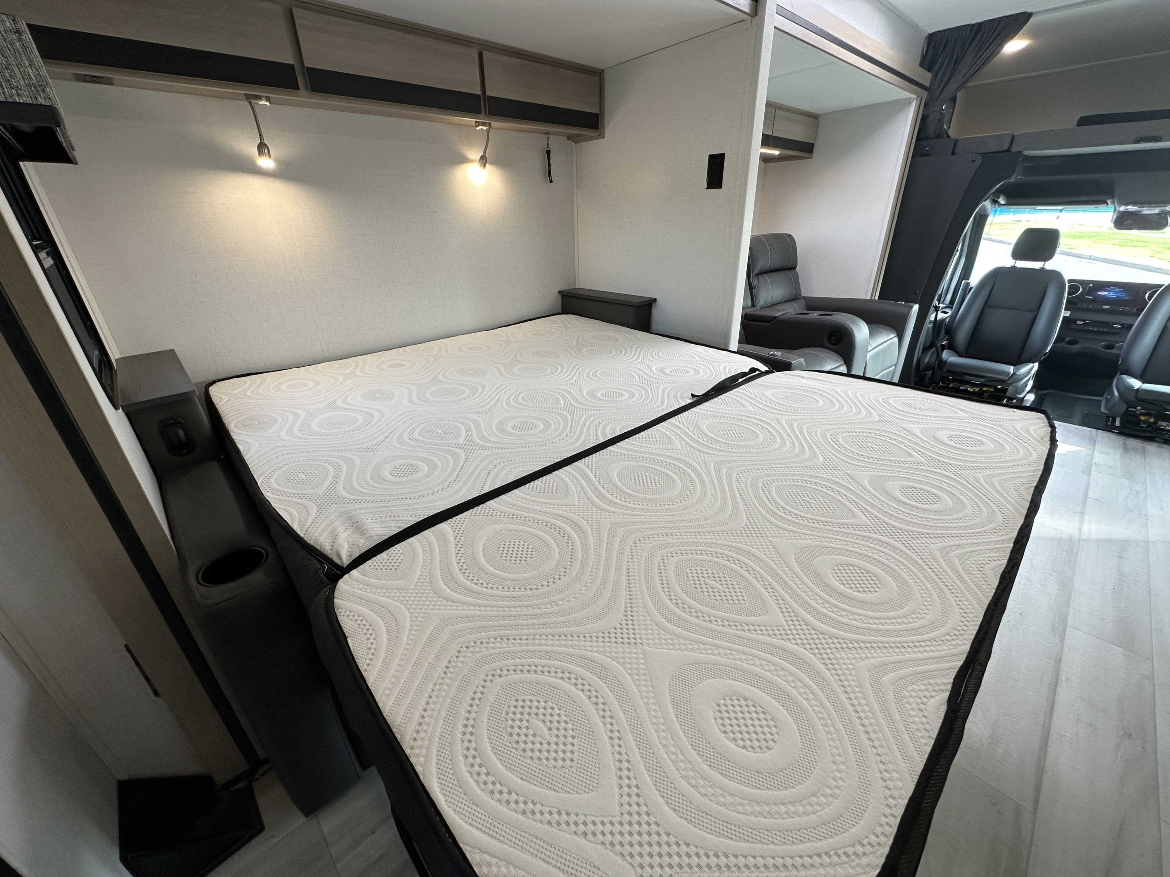 Comfortable RV rental interior with two convertible beds, overhead storage, and a cozy seating area near the driver's cabin.. Forest River Sunseeker 2024