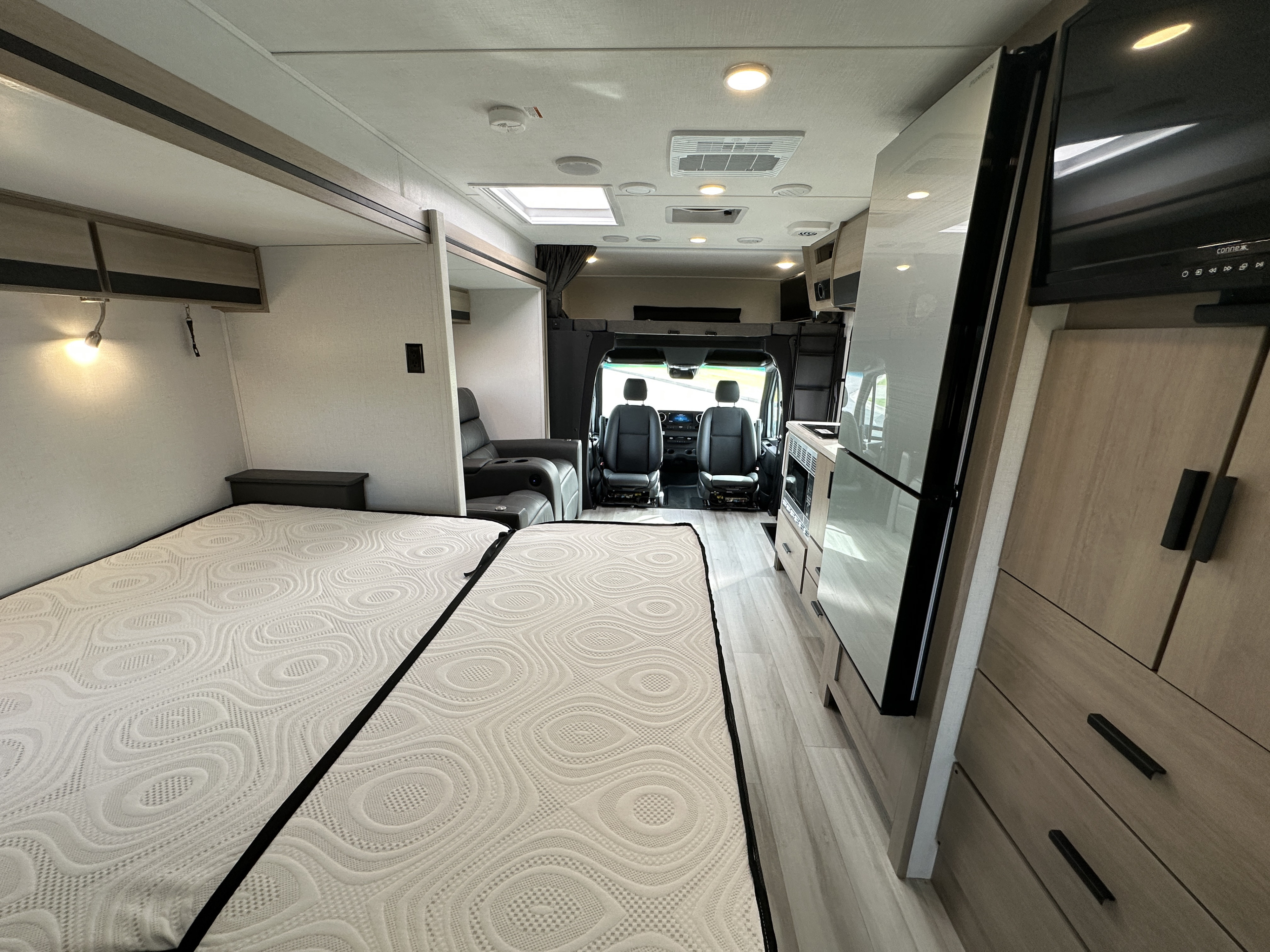 Bright, modern rv rental interior with twin beds, full kitchen, and front cockpit seats. Explore in comfort.. Forest River Sunseeker 2024