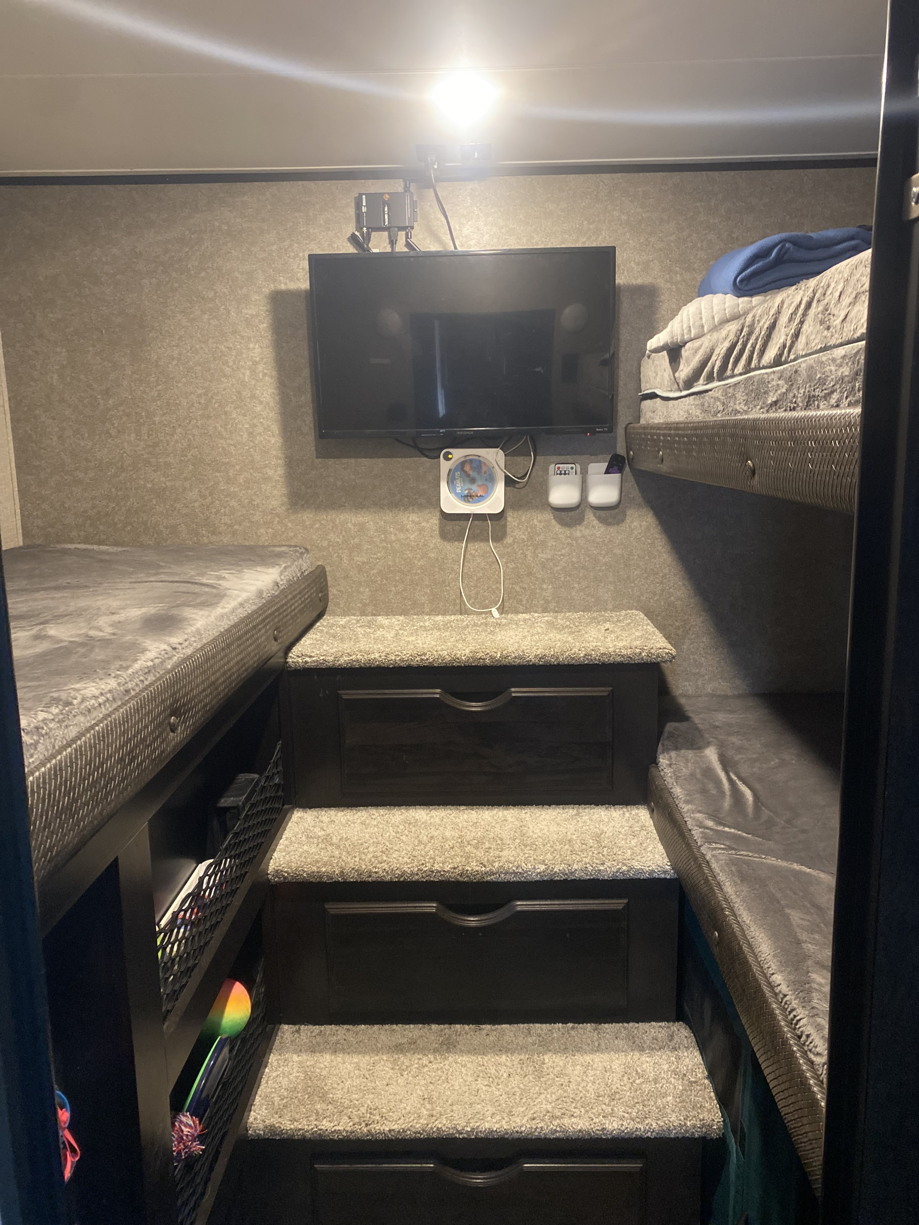 RV rental bunkhouse interior with TV, stair storage, and multiple beds, ideal for family travel.. Jayco Eagle HT 2021