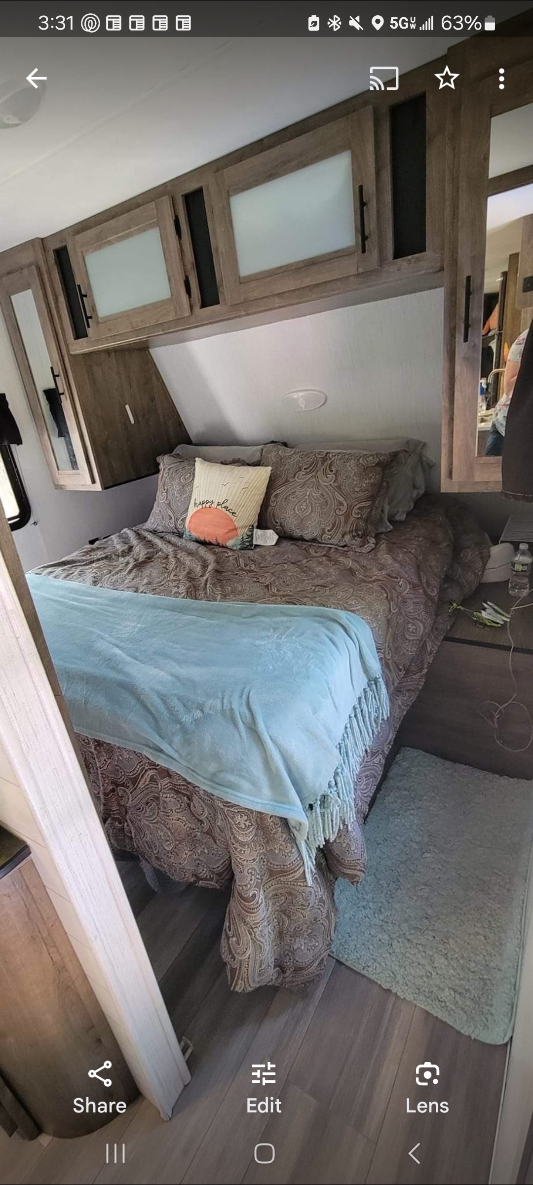 Comfortable RV rental bedroom: brown patterned bed, light blue blanket, and wooden overhead cabinets with frosted panels.. Heartland RVs Pioneer 2021