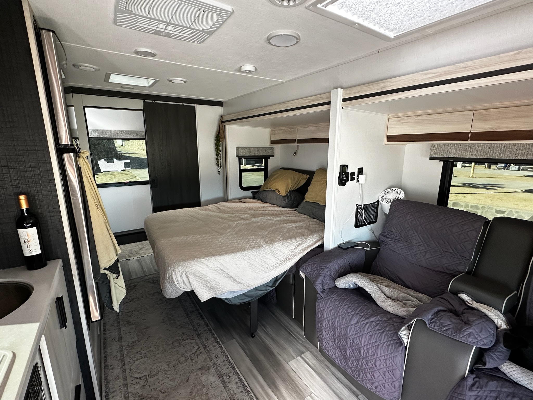 Cozy RV rental interior with a queen bed, comfy recliner sofa, and small kitchen. Ideal for road trips.. Forest River Mercedes 3500XD 2401T 2023