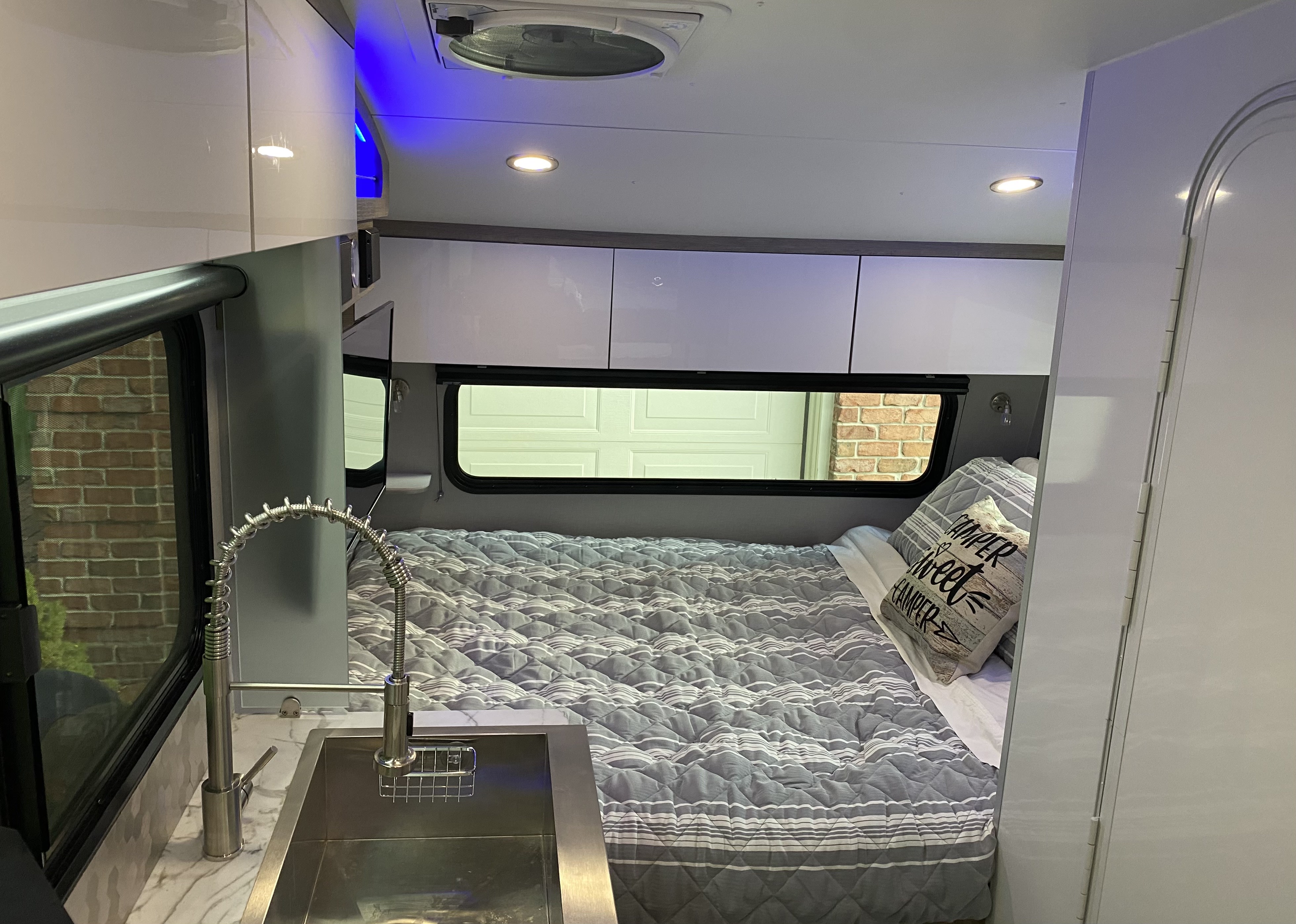 Inside a modern **rv rental**, featuring a cozy bed, sleek kitchen sink, overhead storage, and ambient lighting.. InTech Sol Horizon 2023