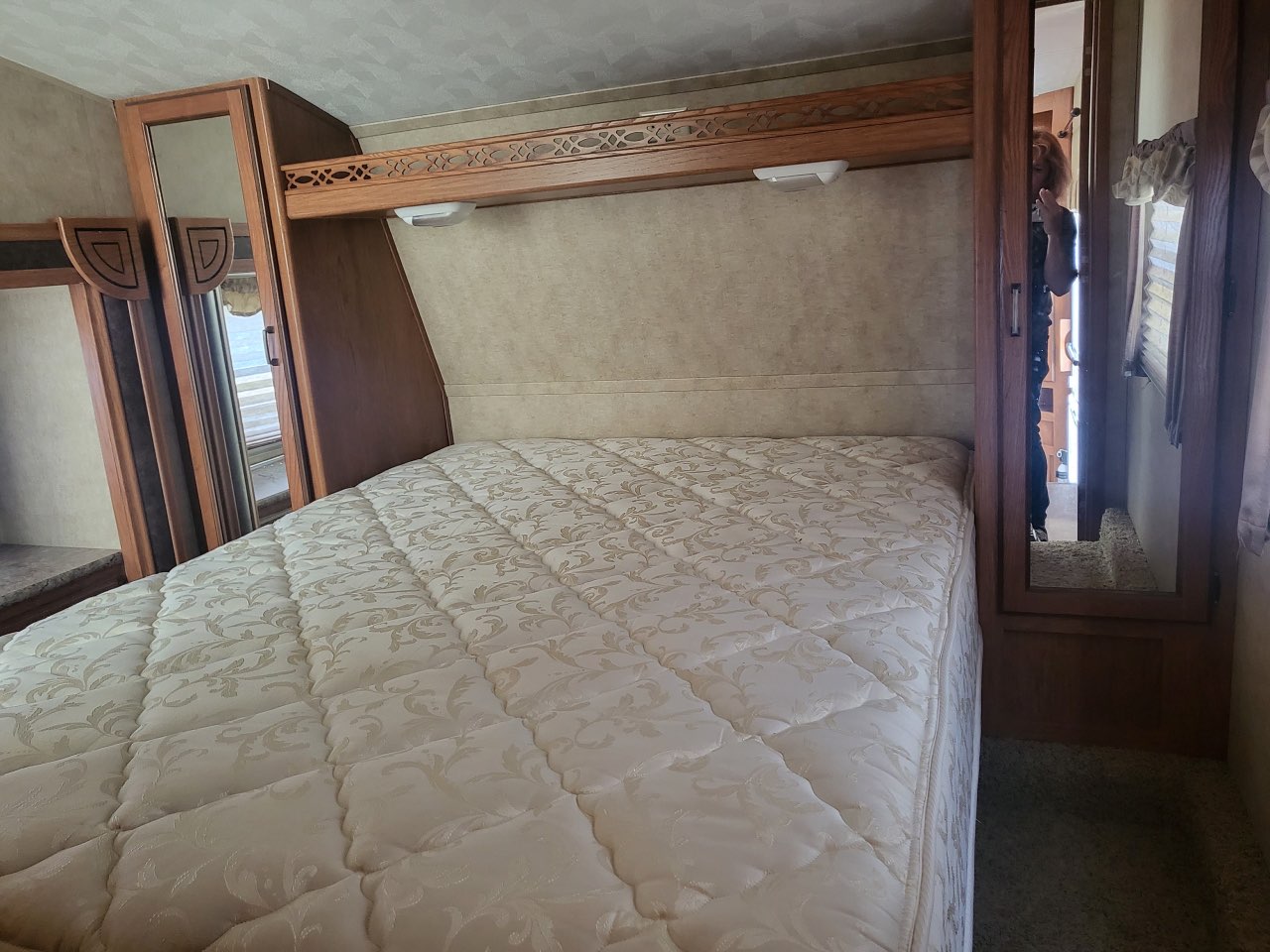 This RV rental bedroom offers a comfortable bed, wooden cabinetry, and overhead storage for a cozy travel experience.. Forest River Palomino Sabre Silhouette 2013