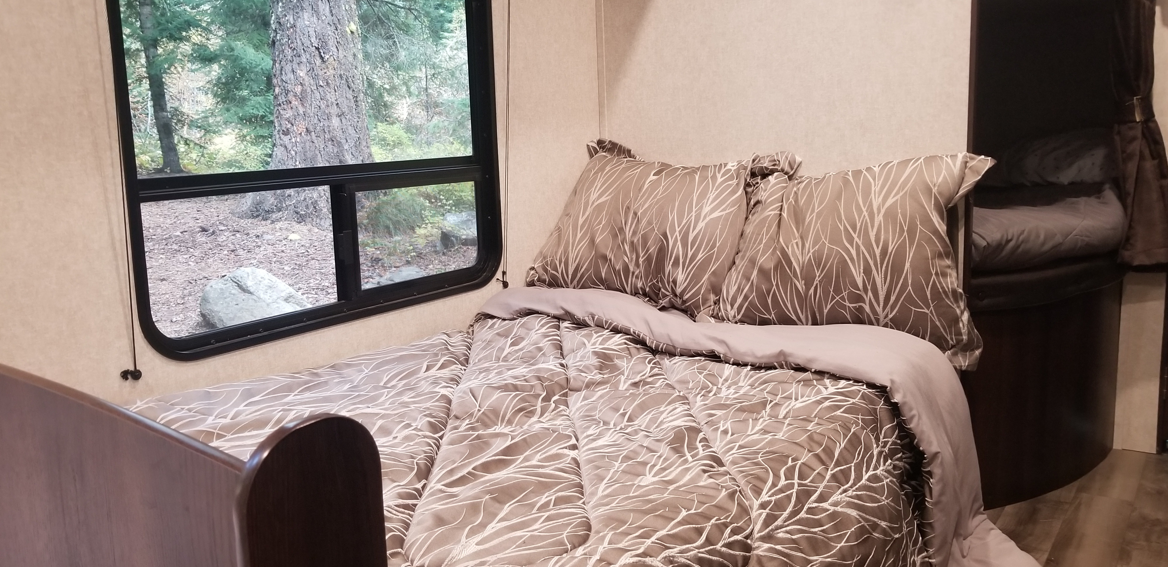 Cozy RV rental bedroom featuring a patterned bed, nature view from window, and adjacent bunk area.. Jayco Jay Flight SLX 2019