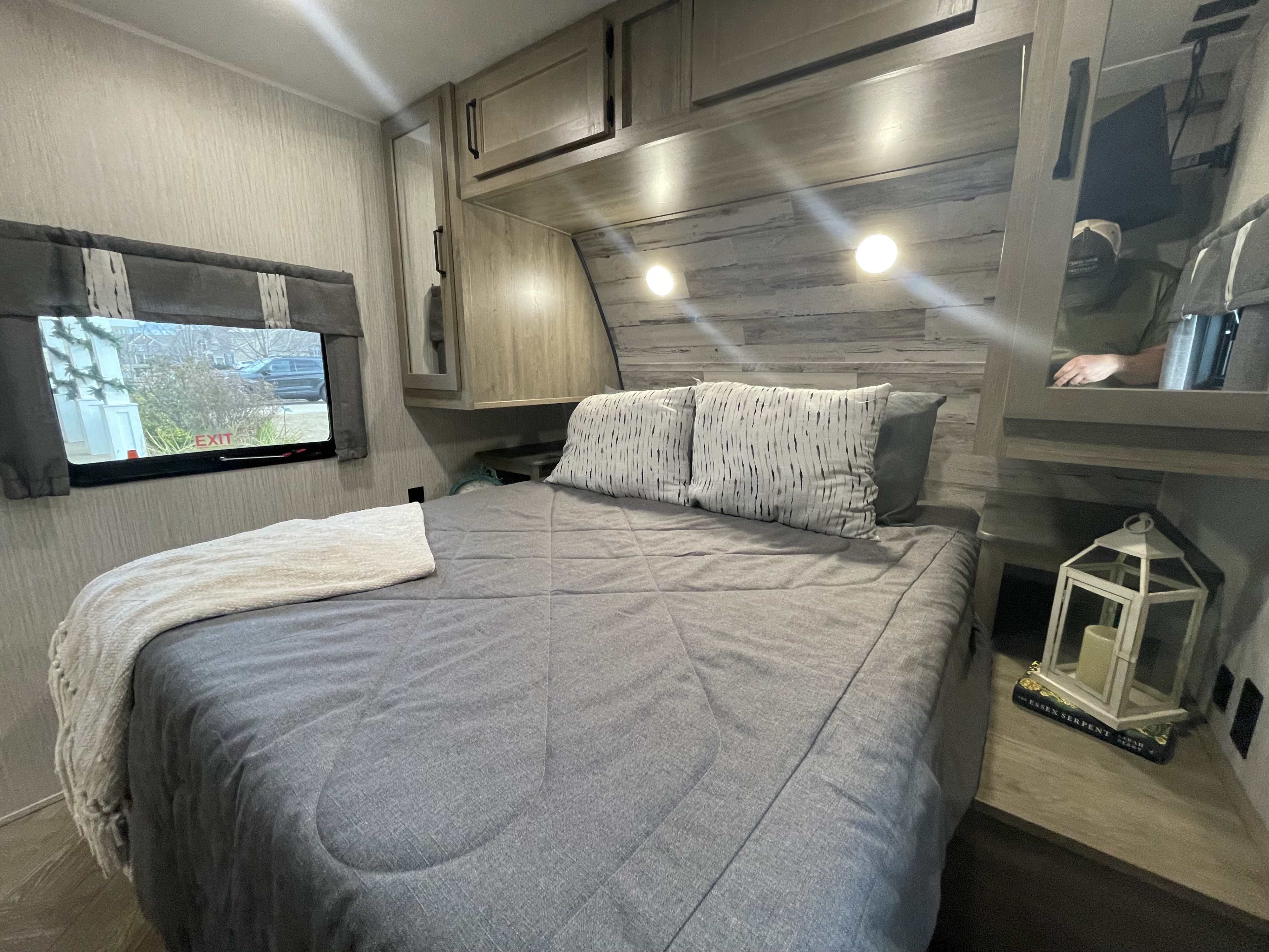 Modern RV rental bedroom with a gray bed, ample storage, ambient lighting, and a window view.. Forest River Palomino Puma 2023