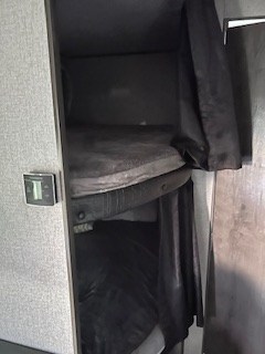 Inside an RV rental, a compact sleeping area features dark-covered bunk beds. A thermostat is on the left wall for comfort.. Jayco Jay Flight SLX 2021