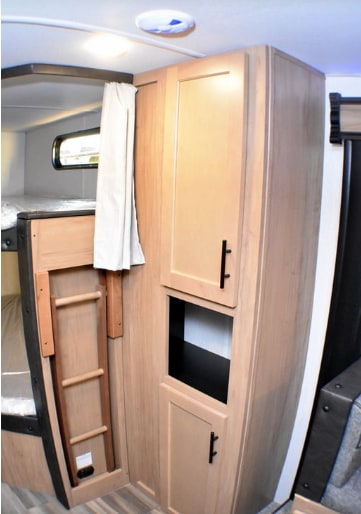 Inside an RV rental: view of bunk beds with a folded ladder, light wood cabinets, and overhead lighting.. Forest River Cherokee Grey Wolf 2023