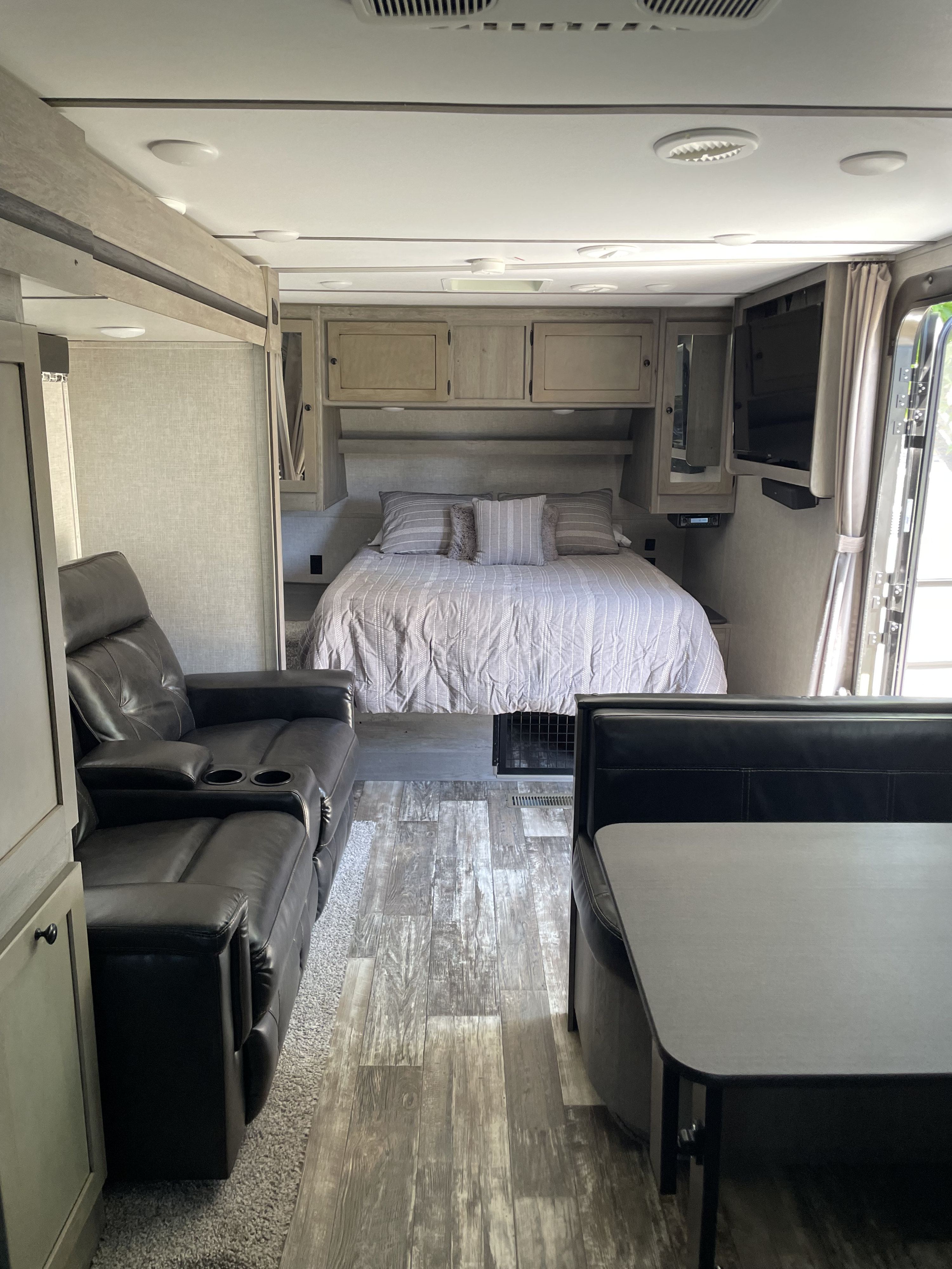 This rv rental features a cozy bedroom with a bed, comfortable recliner sofa, and a dinette booth, showcasing a spacious interior.. Keystone RV Outback Ultra-Lite 2019