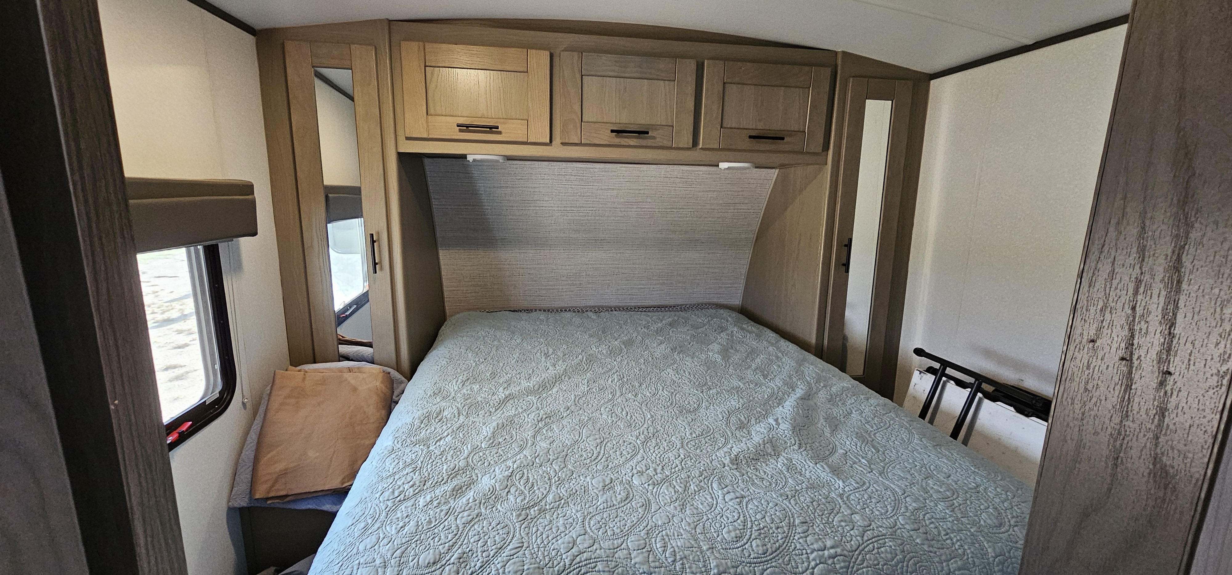 Cozy RV bedroom interior featuring a comfortable bed, overhead cabinets, and a window, ideal for an RV rental adventure.. Cruiser RV Shadow Cruiser 2021