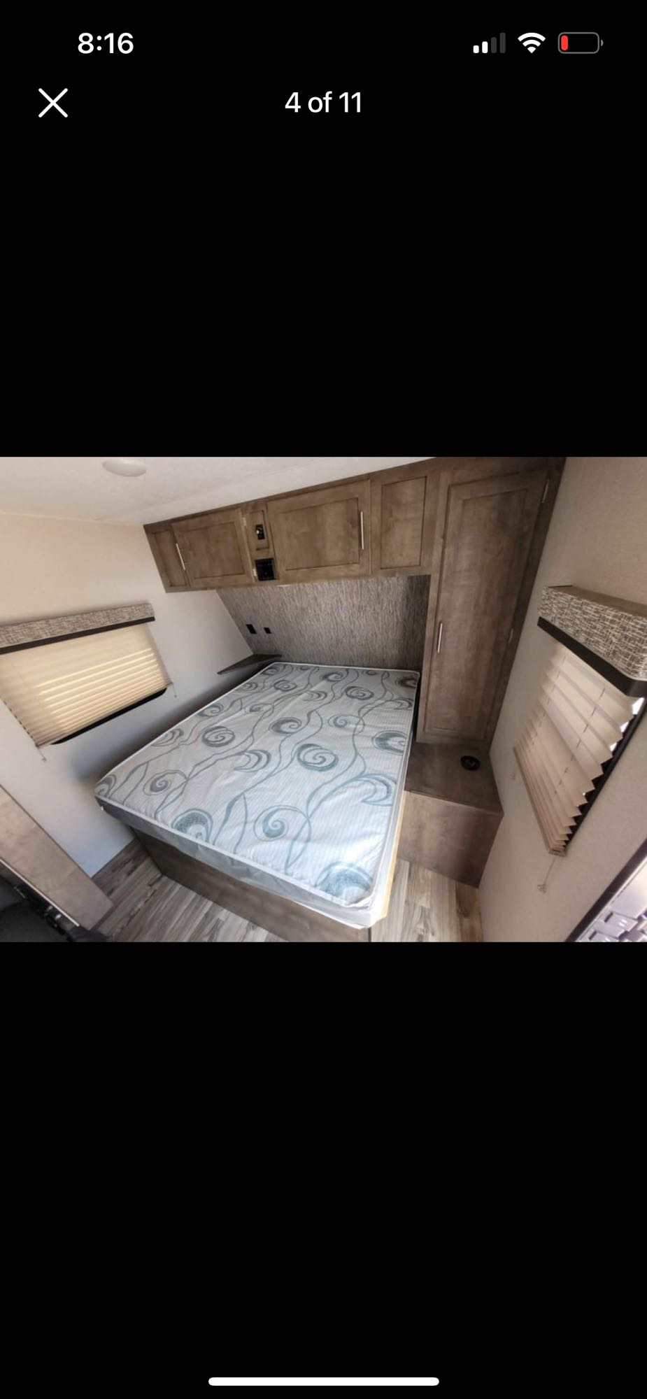 Inside an RV rental bedroom: A neatly made bed with patterned mattress, overhead cabinets, and windows with blinds.. KZ Escape 2019