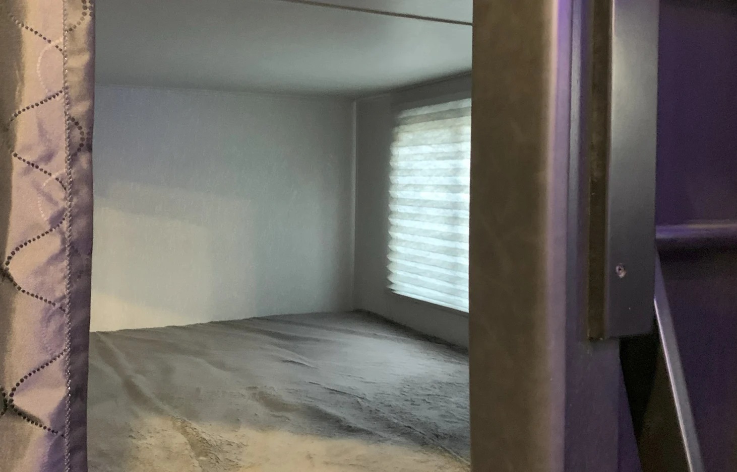 Compact RV rental sleeping area. Patterned curtain, window with blinds, and soft bed visible.. Forest River Cherokee Grey Wolf 2021