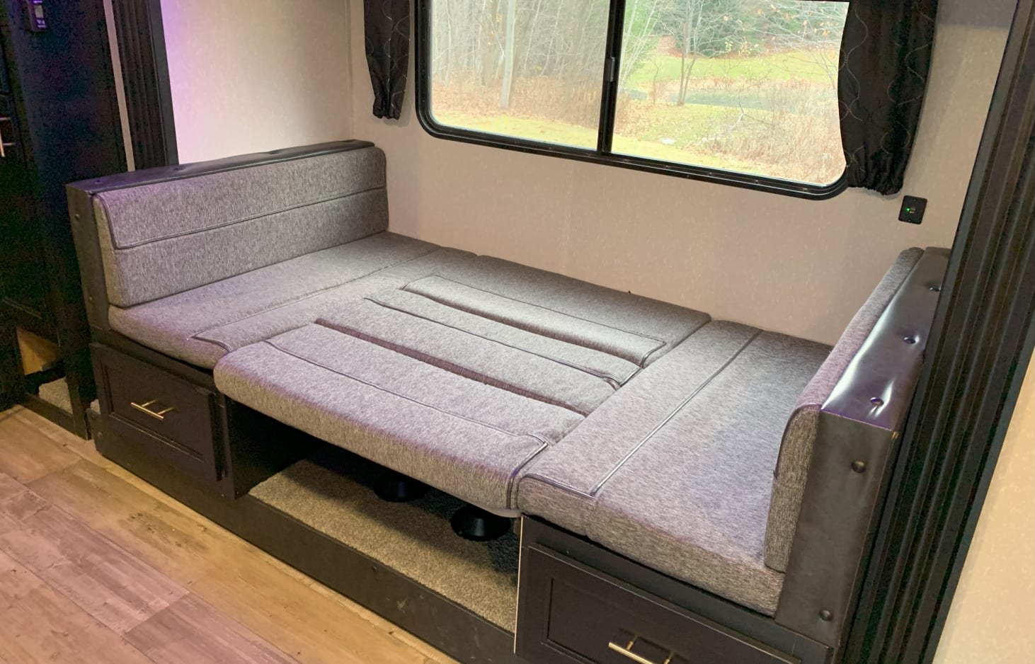 Spacious RV rental interior featuring a gray convertible dinette/sofa bed with storage, offering comfort and utility.. Forest River Cherokee Grey Wolf 2021