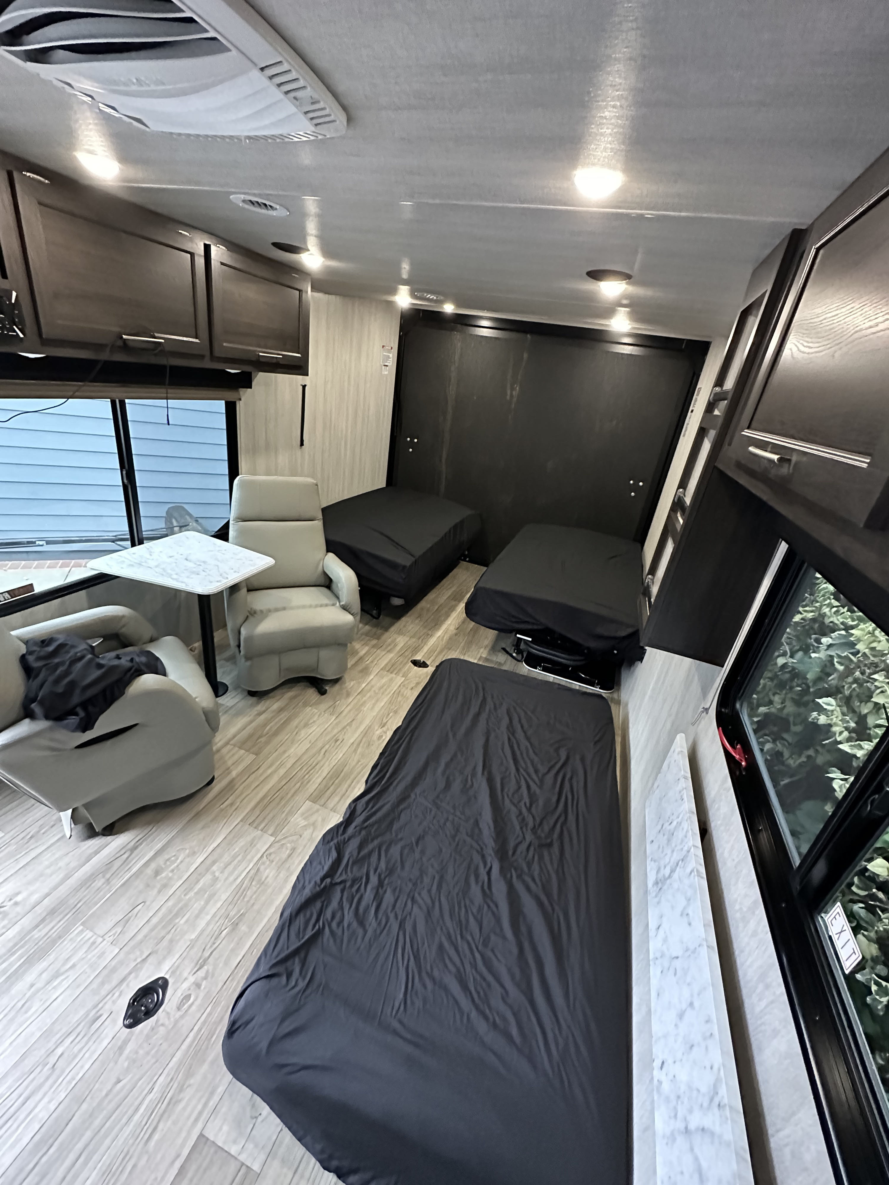 Spacious RV rental interior with recliners, a table, and multiple dark-covered beds, perfect for comfortable travel.. MGM limited by Genesis MFS275 2023