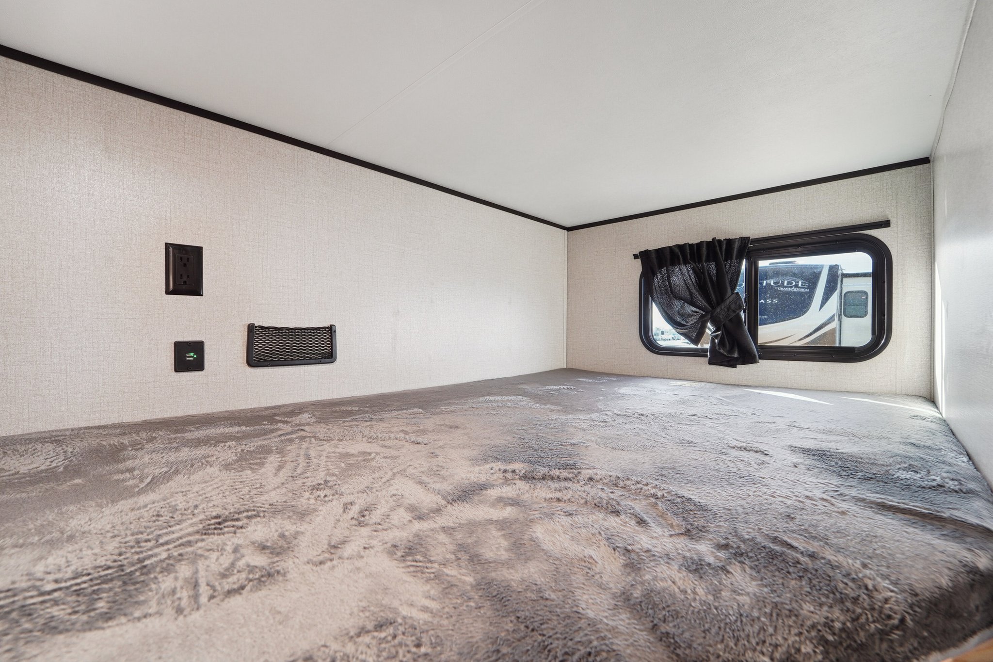 Cozy RV rental bunk bed area featuring a plush mattress, window, power outlets, and storage net.. Wayfinder GoPlay 2024