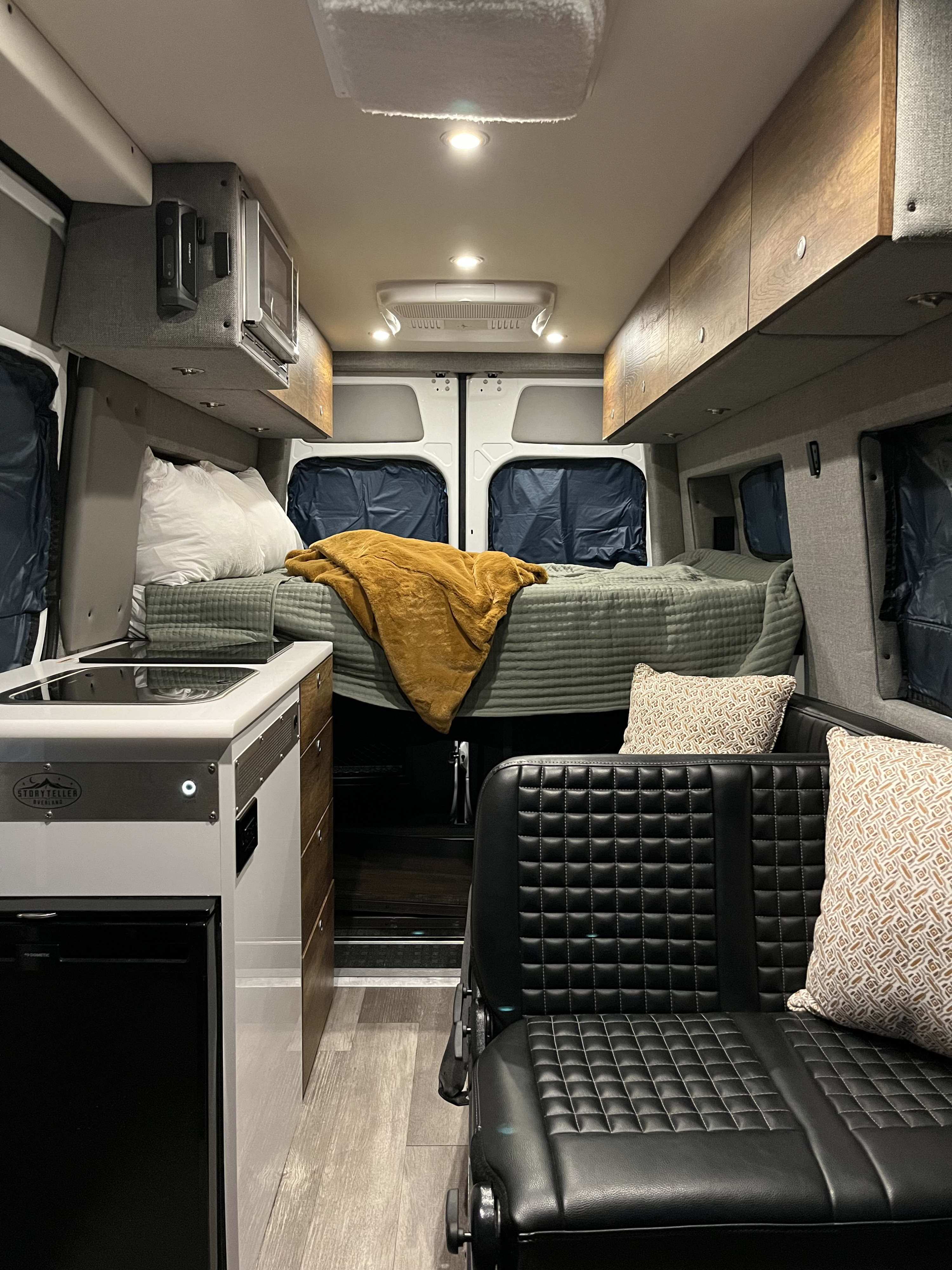 RV rental interior: cozy bed, compact kitchen, and comfy seating inside a modern camper van.. Storyteller Overland Storyteller Overland Class B 2020
