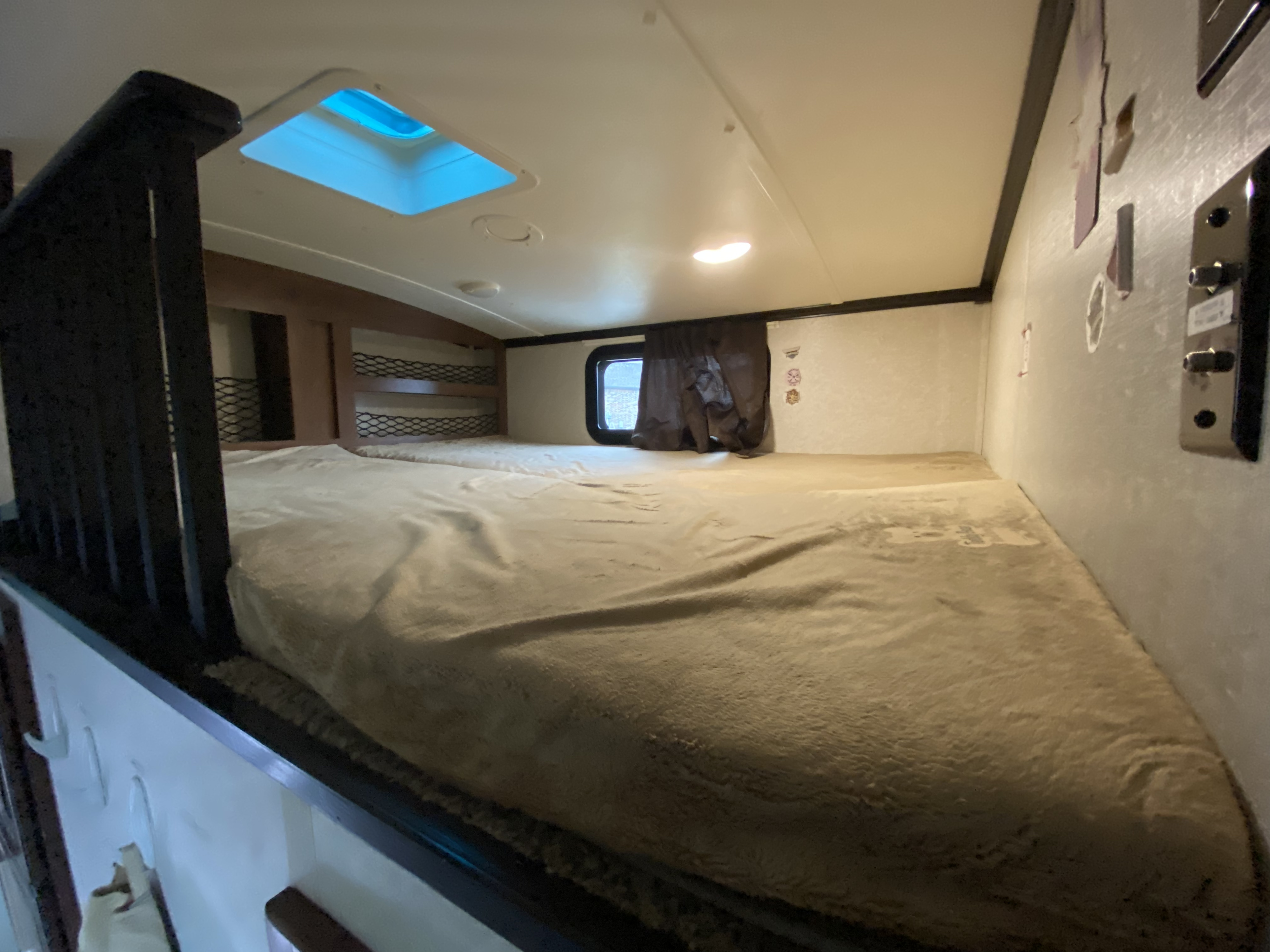 Cozy RV rental bunk bed area with a bright skylight and window, offering a comfortable sleeping space for your adventure.. Jayco North Point 2017