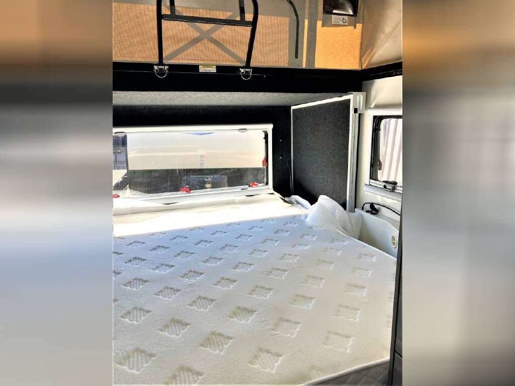 RV rental interior: A comfortable bedroom with a large, white patterned mattress and windows, ready for your next adventure.. OBI OBI Popup Trailer 2022