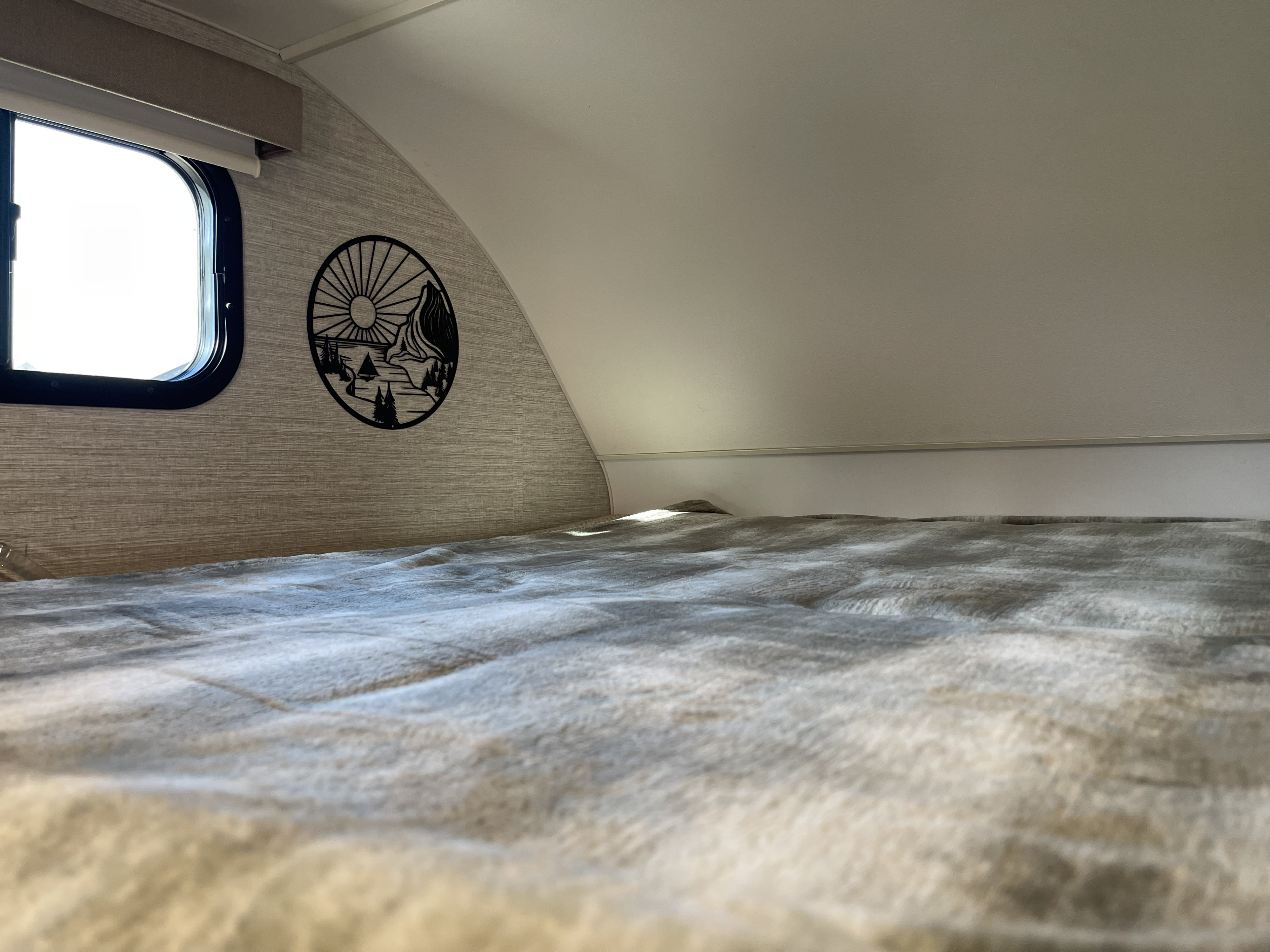 Cozy RV rental sleeping area with a comfortable bed, large window, and mountain-themed wall art, ready for adventure.. Winnebago Minnie Winnie 2024