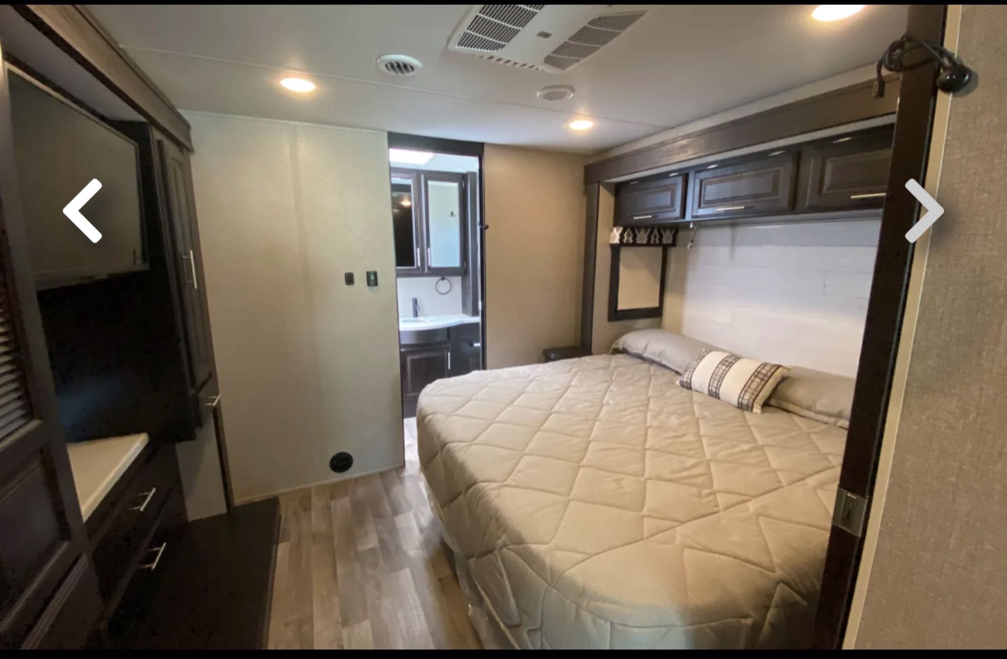 RV rental bedroom: Features a comfortable bed, overhead cabinets, built-in dresser, and en-suite bathroom view.. Jayco Precept 2021