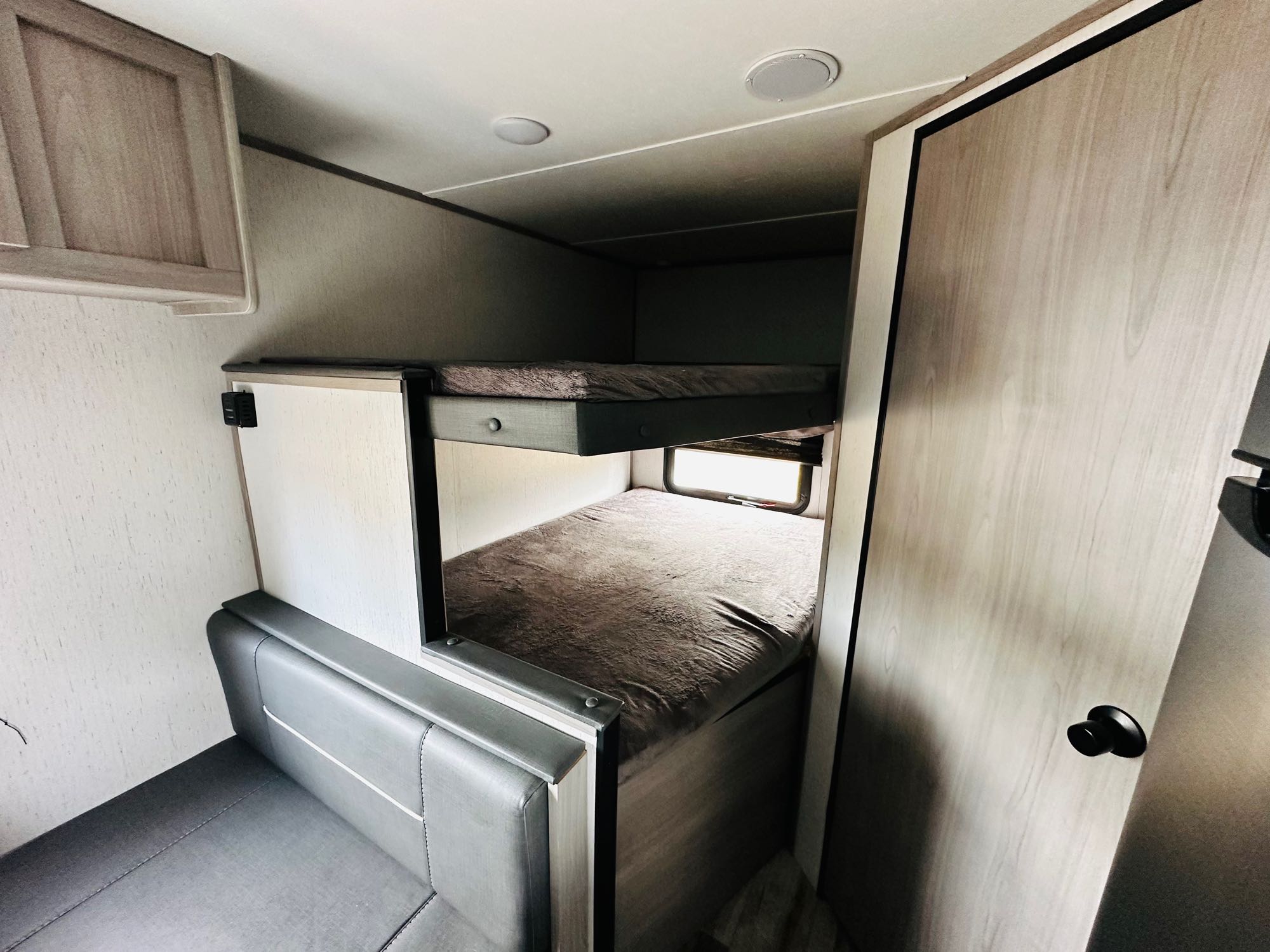 Spacious RV rental bunk beds & seating area. Perfect for families, this travel trailer interior offers comfort & practicality.. Dutchmen Coleman Lantern LT 2022