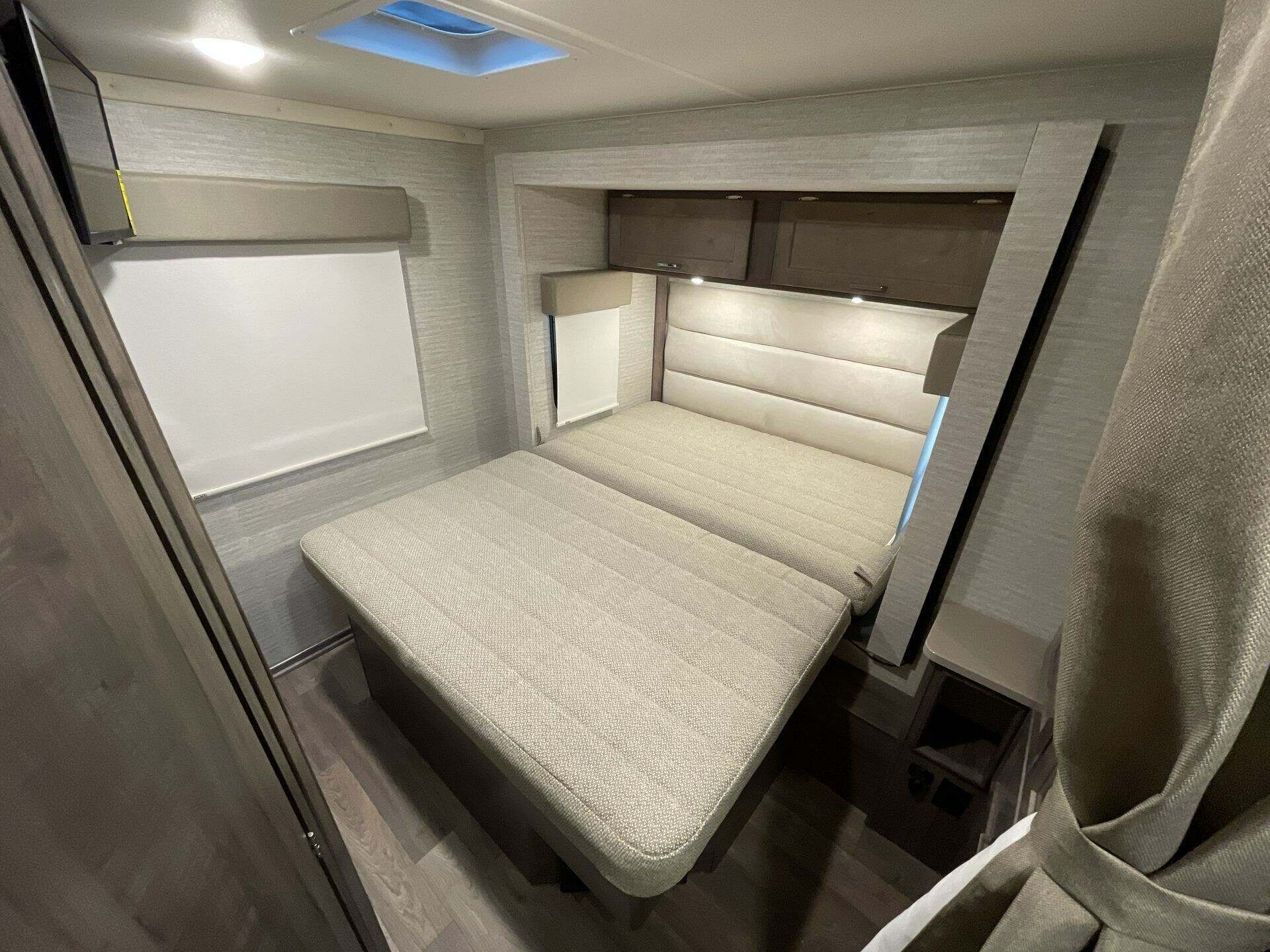 RV rental bedroom with comfortable modular bed, wall-mounted TV, and ample storage, perfect for your next trip.. Winnebago Minnie Winnie 22M 2024