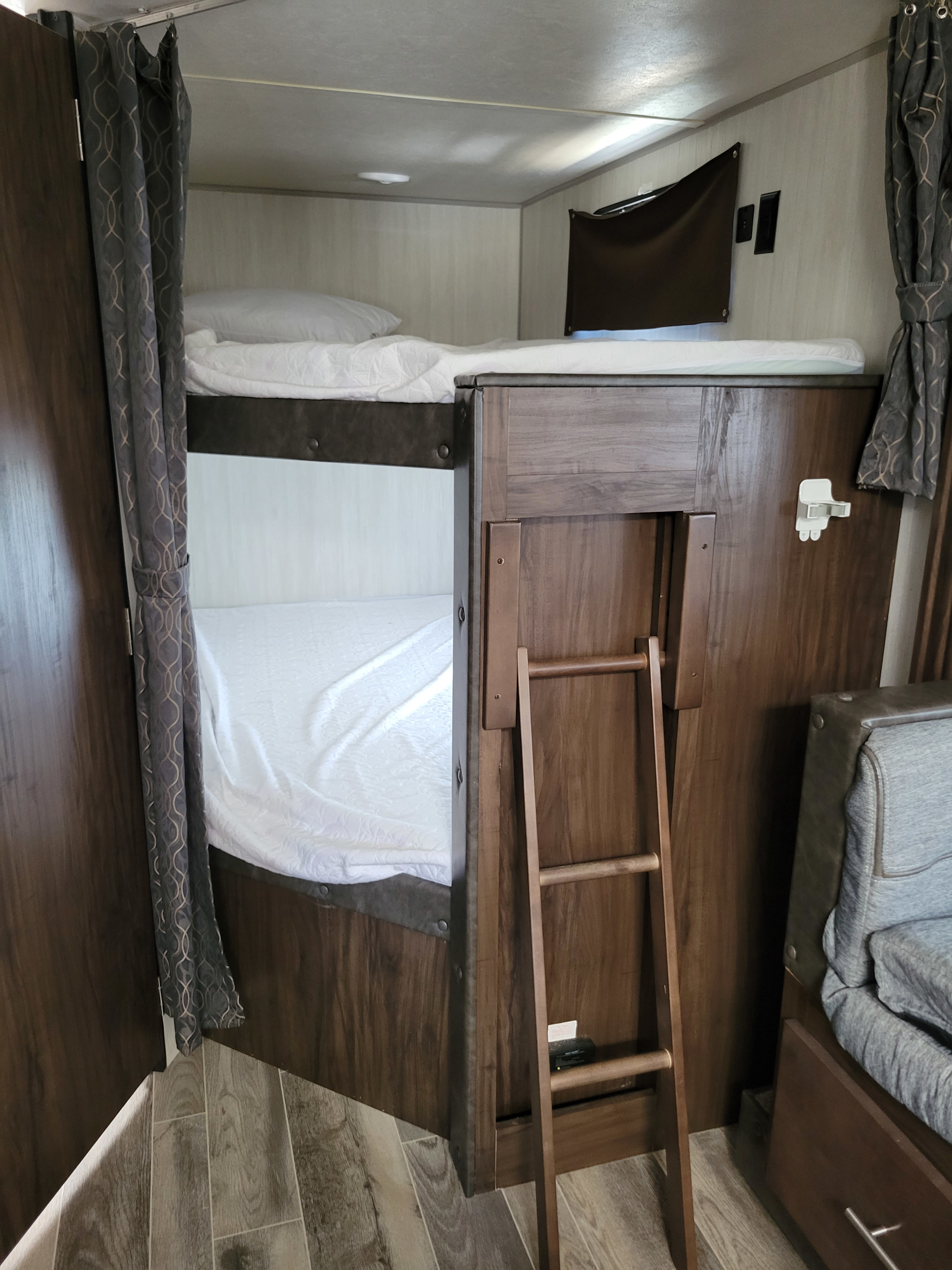 RV rental: This image showcases a compact bunk bed setup inside an RV, complete with white bedding, pillows, and a wooden access ladder, offering a cozy sleeping area.. Forest River Cherokee Grey Wolf 2019
