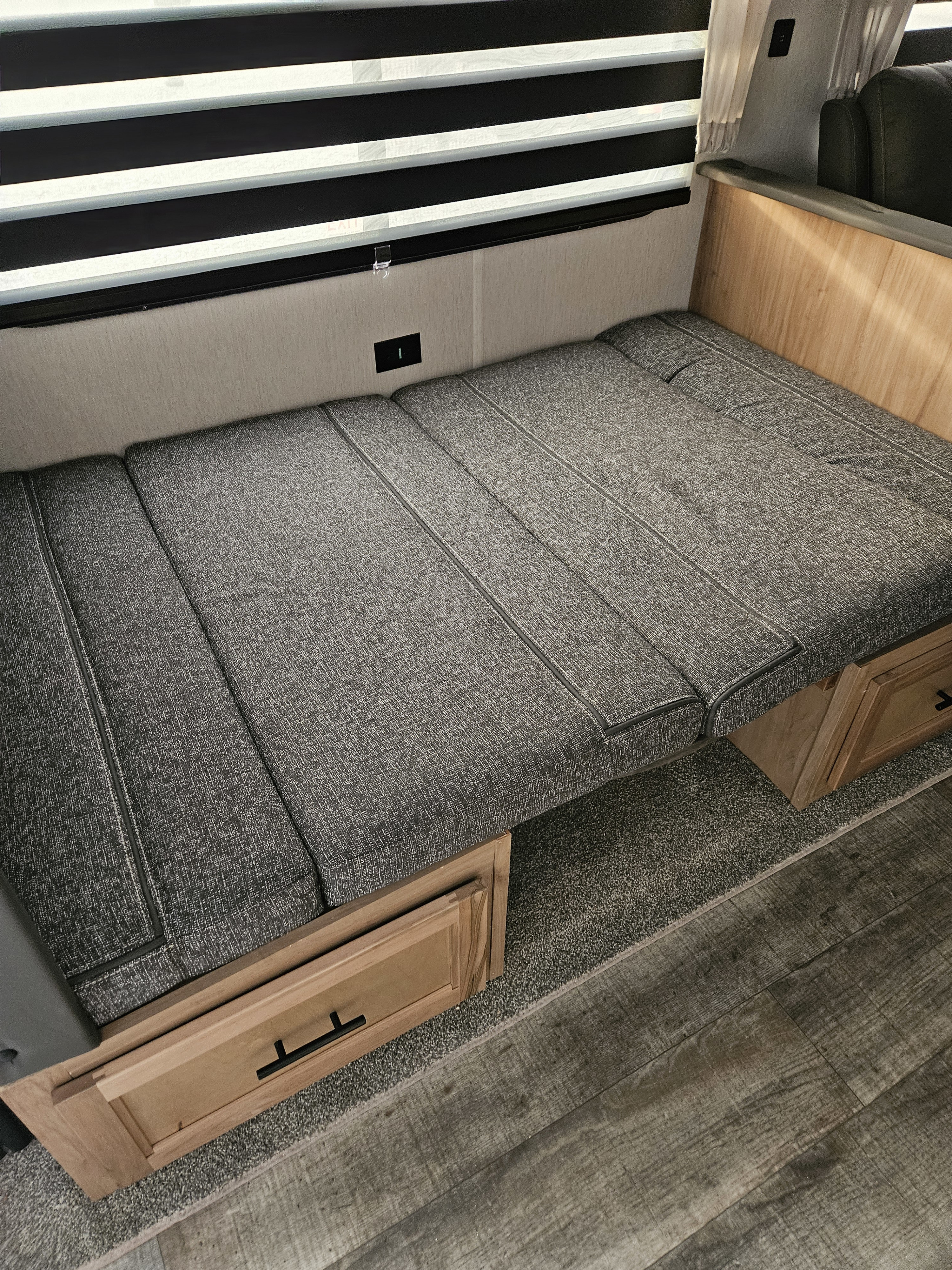 **RV rental** interior featuring a gray dinette bed with under-seat storage, blinds, and an outlet.. Forest River Cherokee Grey Wolf 2023