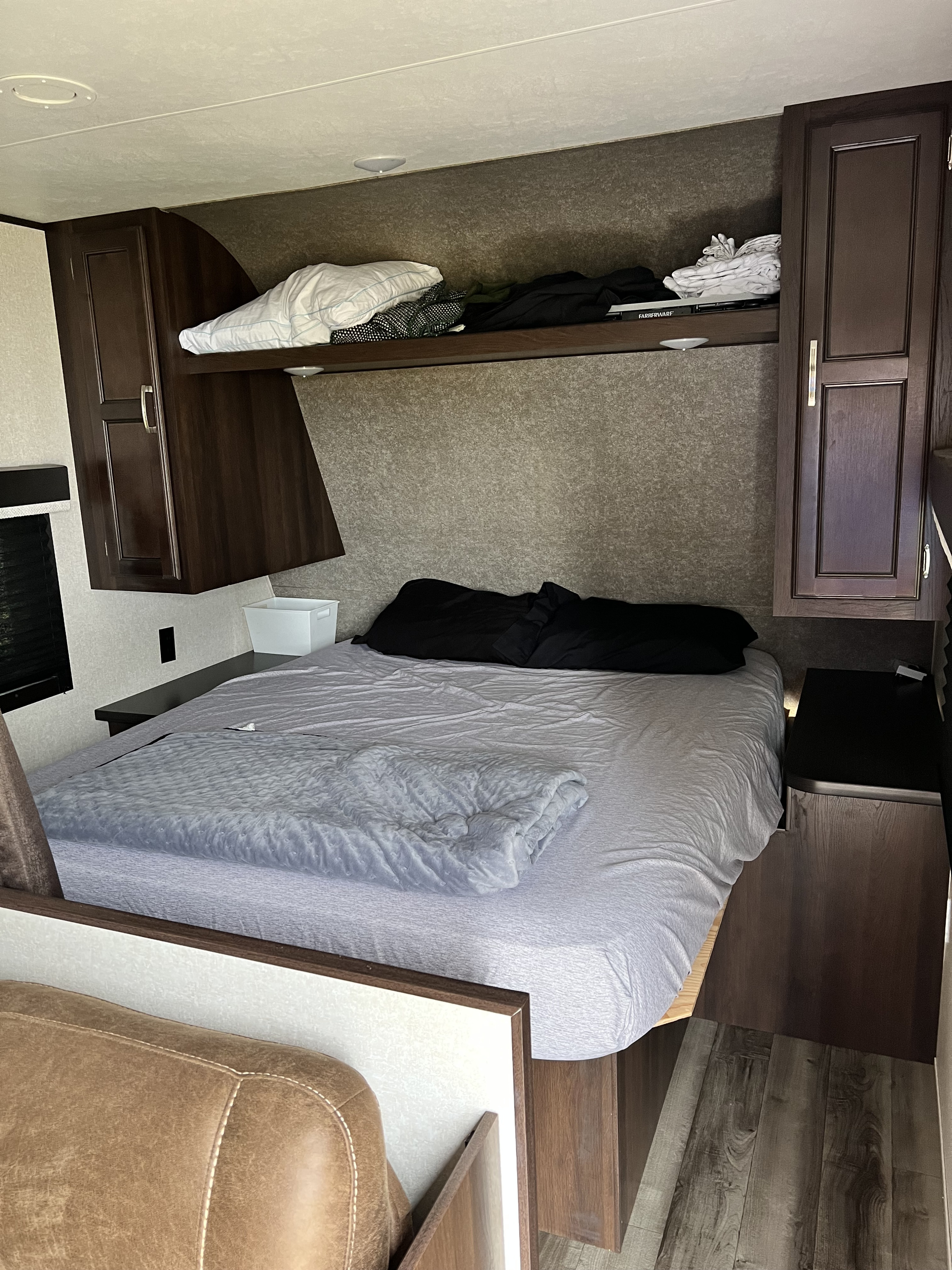Cozy RV rental bedroom with a comfortable bed, pillows, overhead storage, and dark wood cabinetry for your journey.. Jayco Jay Flight SLX 2020