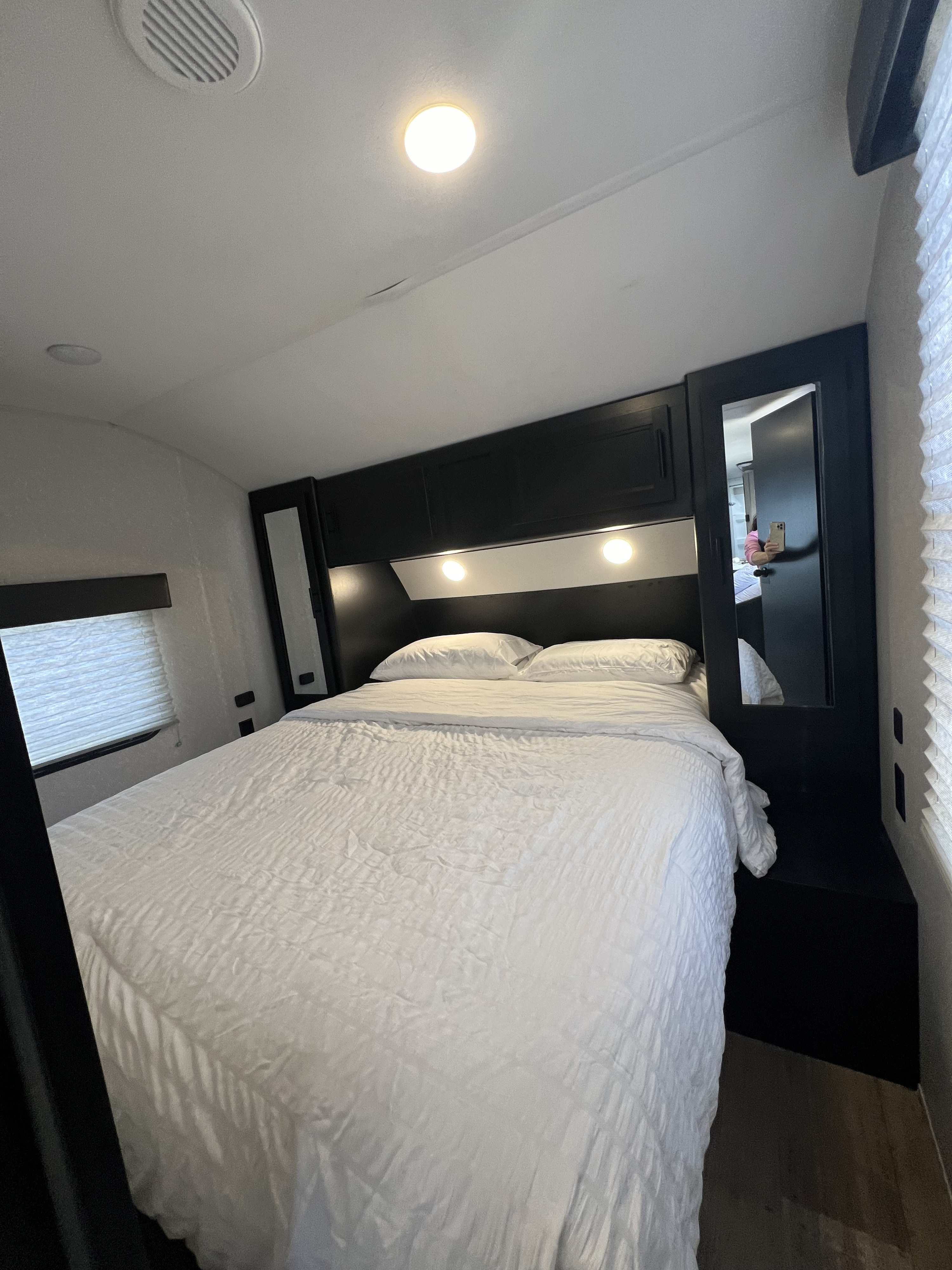 Modern RV rental bedroom featuring a large white bed, sleek black storage, and ambient lighting.. Forest River Cherokee 2022
