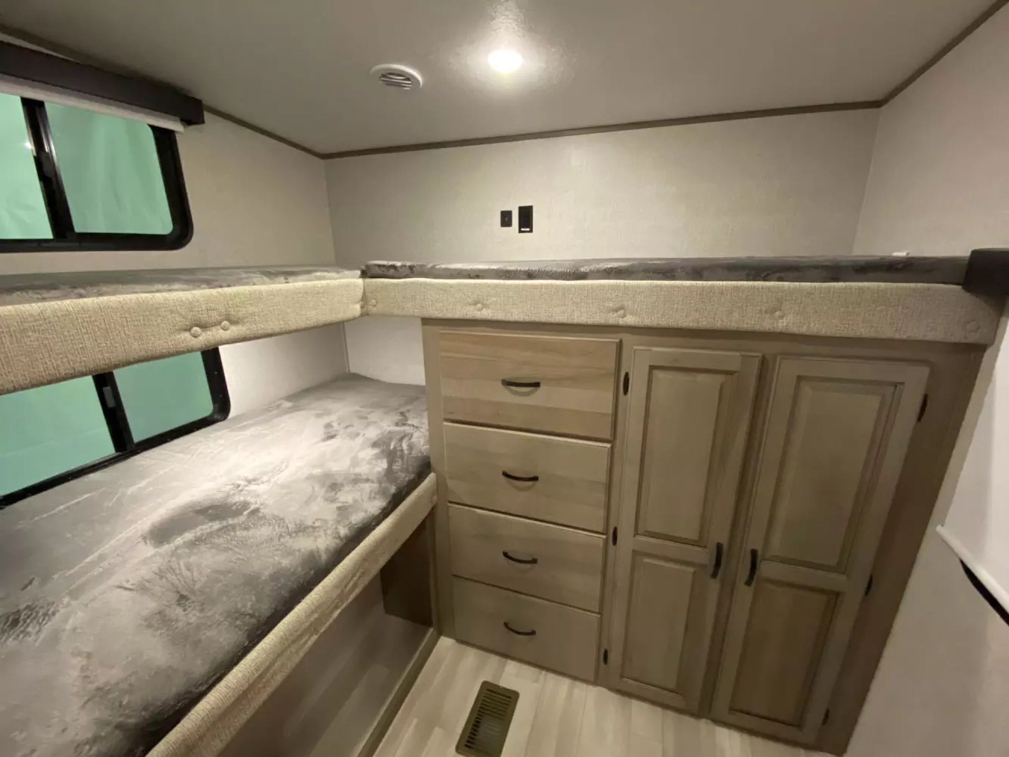 RV rental interior: comfy bunk beds with windows, plus built-in drawers and wardrobe storage for an organized space.. Forest River Coachmen Chaparral Lite 2022