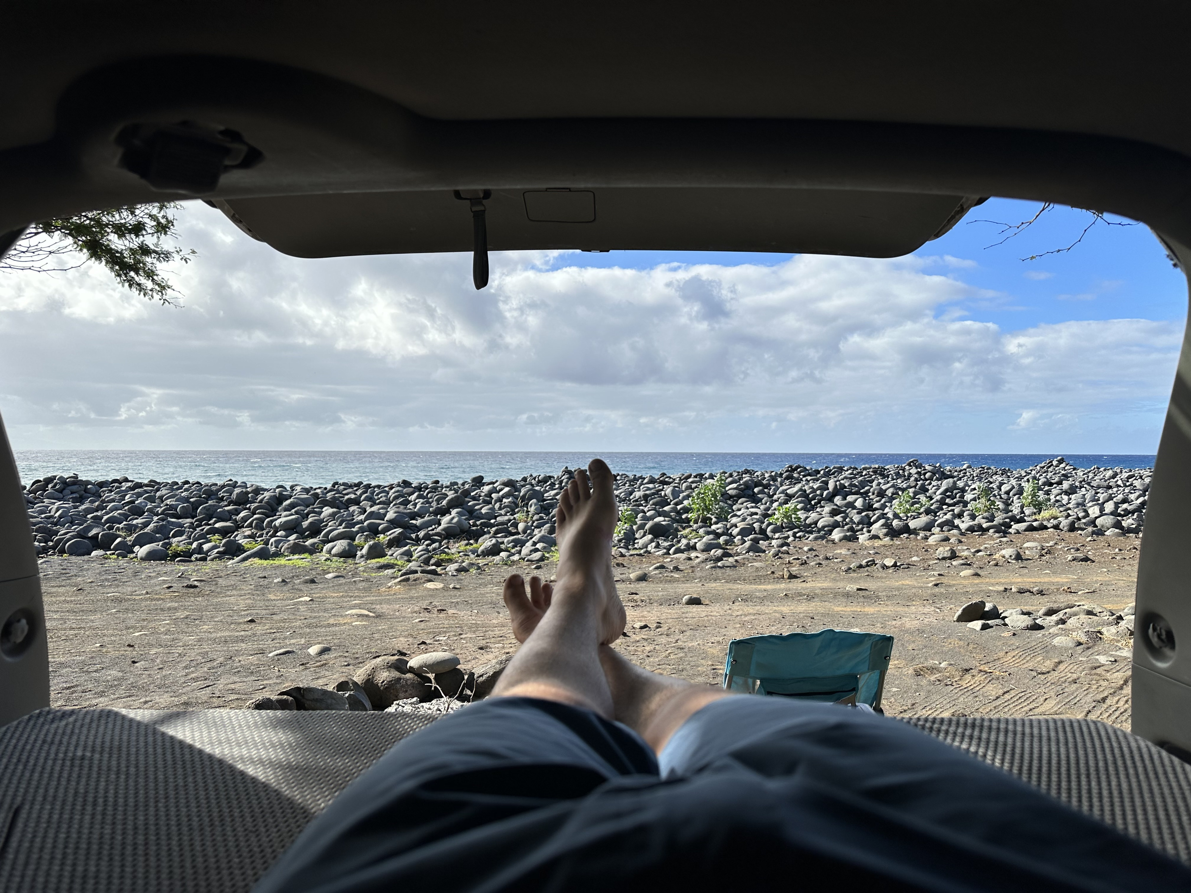 Peaceful ocean view from an RV rental. Feet up, looking out at a rocky beach and the sea under cloudy skies.. Toyota Other 2006