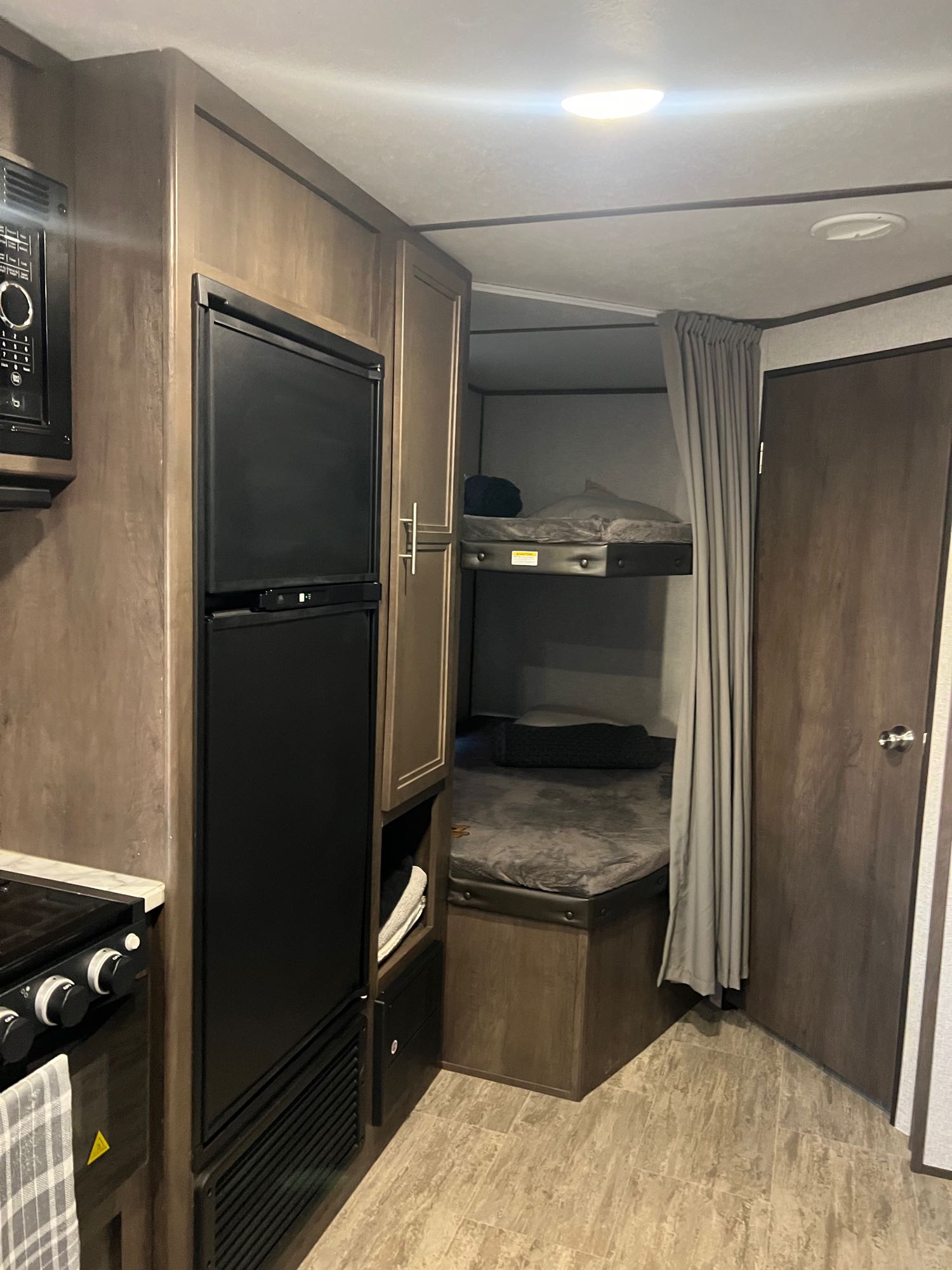Interior of a modern rv rental featuring a compact kitchen, built-in fridge, and cozy bunk beds.. Aspen Trail Aspen Trail Trailer 2021