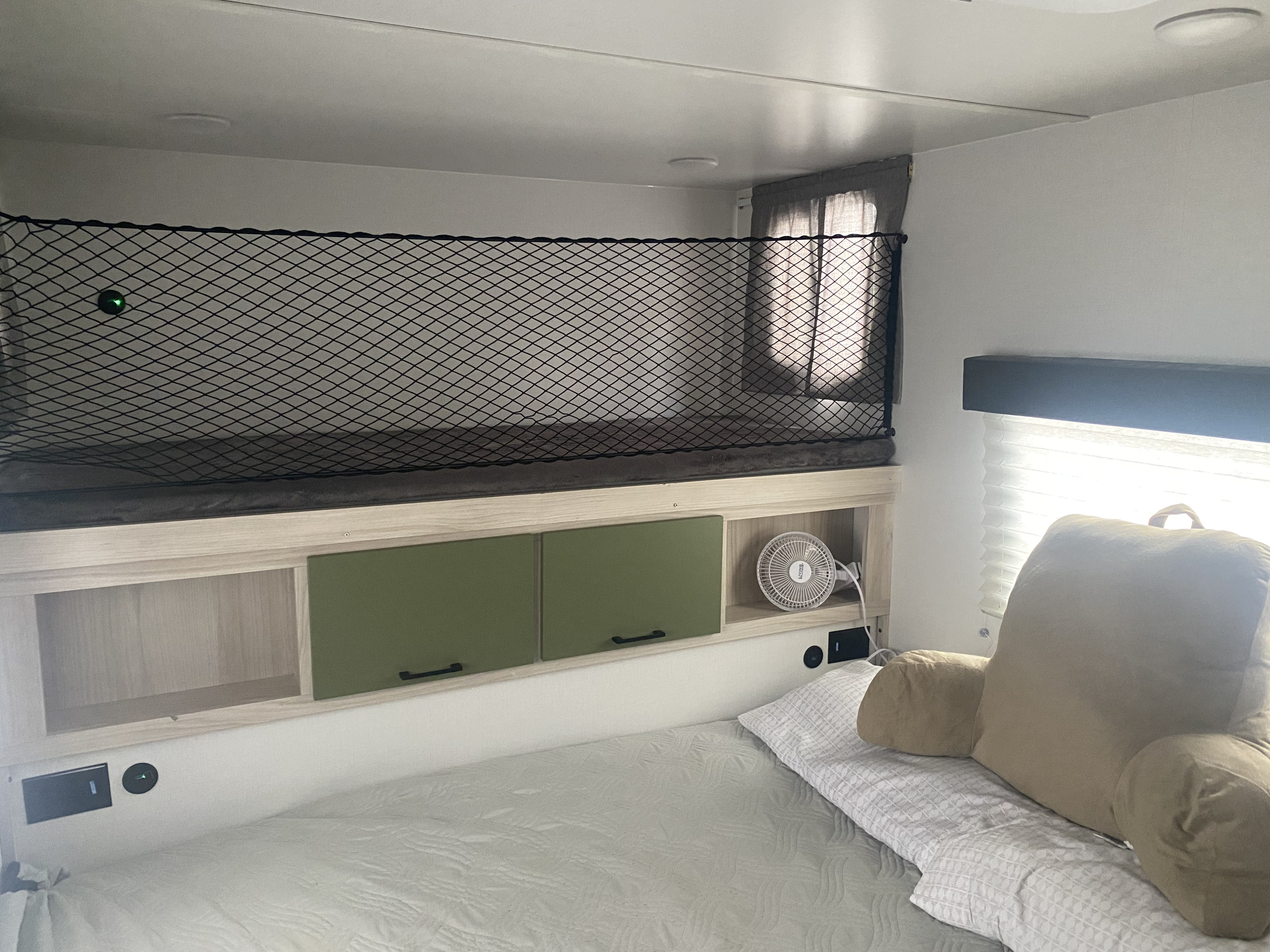 Explore this RV rental's sleeping area, featuring a top bunk with safety net, ample storage, and a comfy main bed.. Winnebago Hike 101 2023