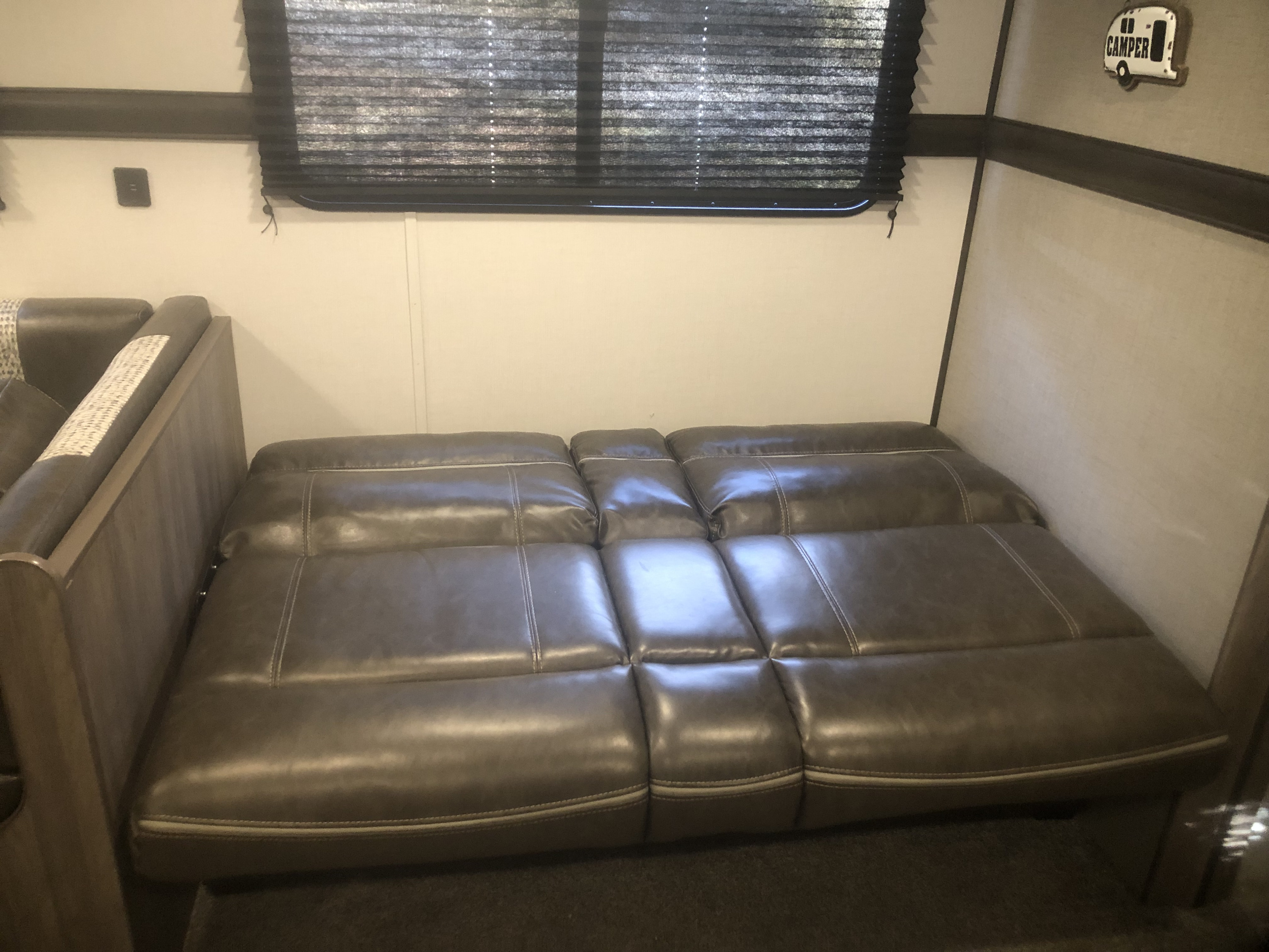 Dark brown leather sofa bed, extended flat in this RV rental's cozy interior, offering comfortable seating or sleeping.. Crossroads RV Zinger Lite 2021