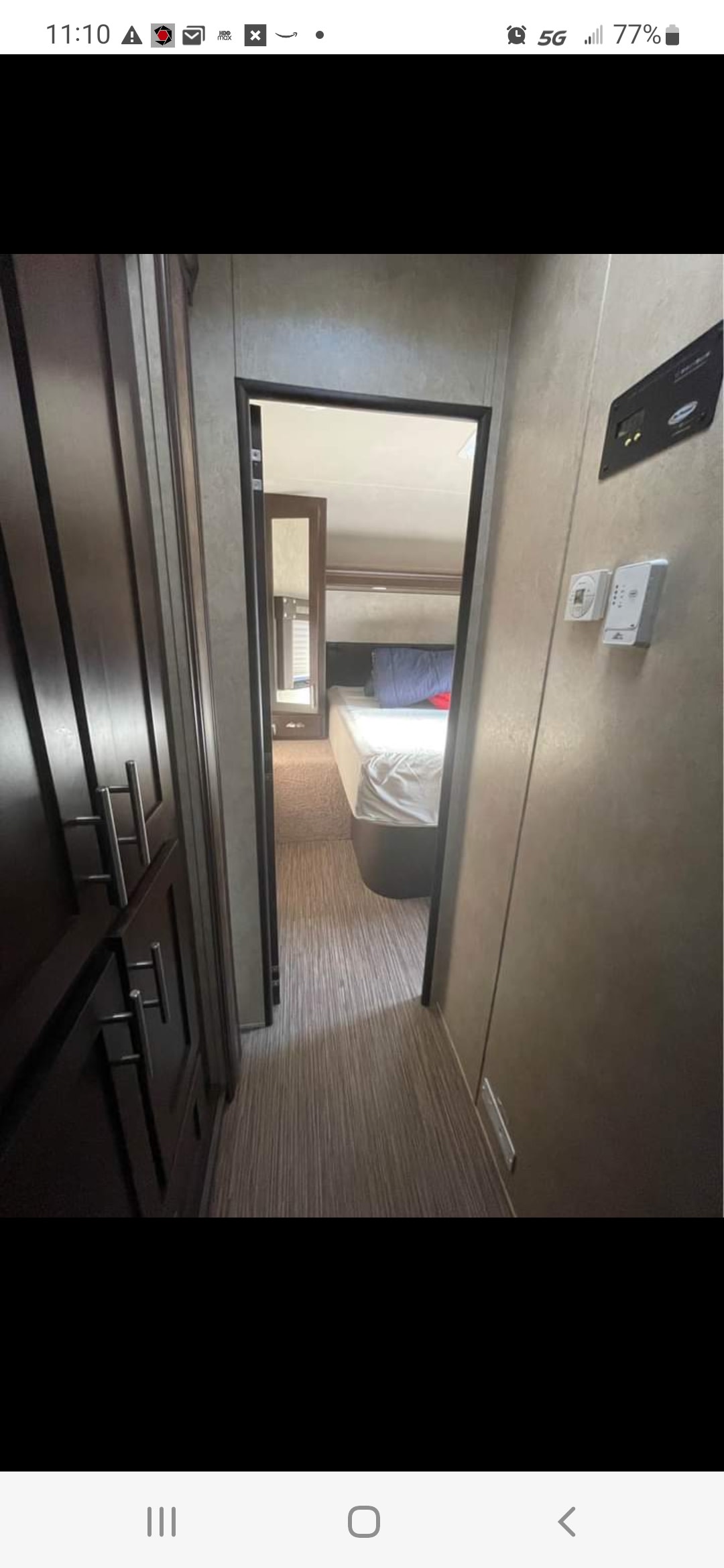 RV rental interior: A hallway with wood-look flooring leads to a private bedroom, with dark cabinets on the left.. Forest River Stealth 2015