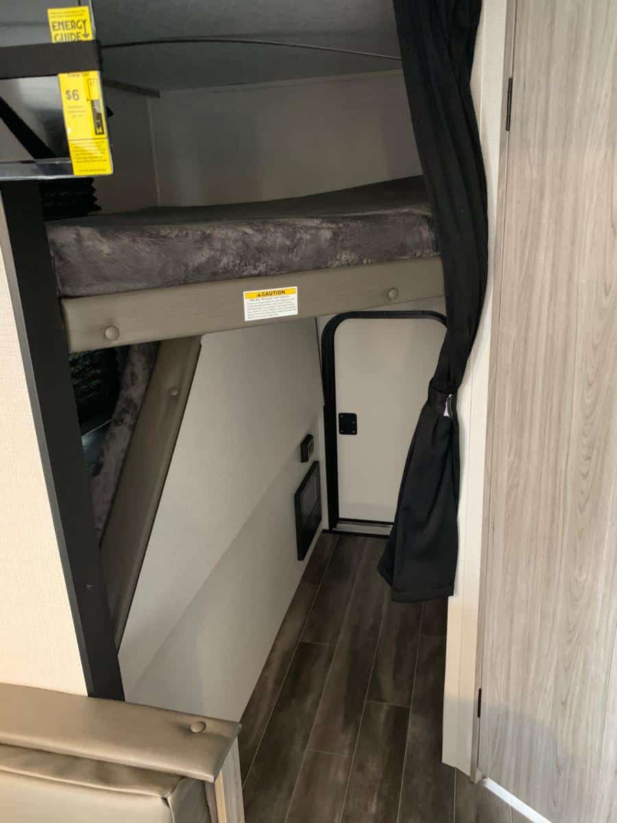 RV rental interior: comfy bunk beds, privacy curtain, and lower door, ideal for camper family trips.. Keystone RV Passport SL 2021