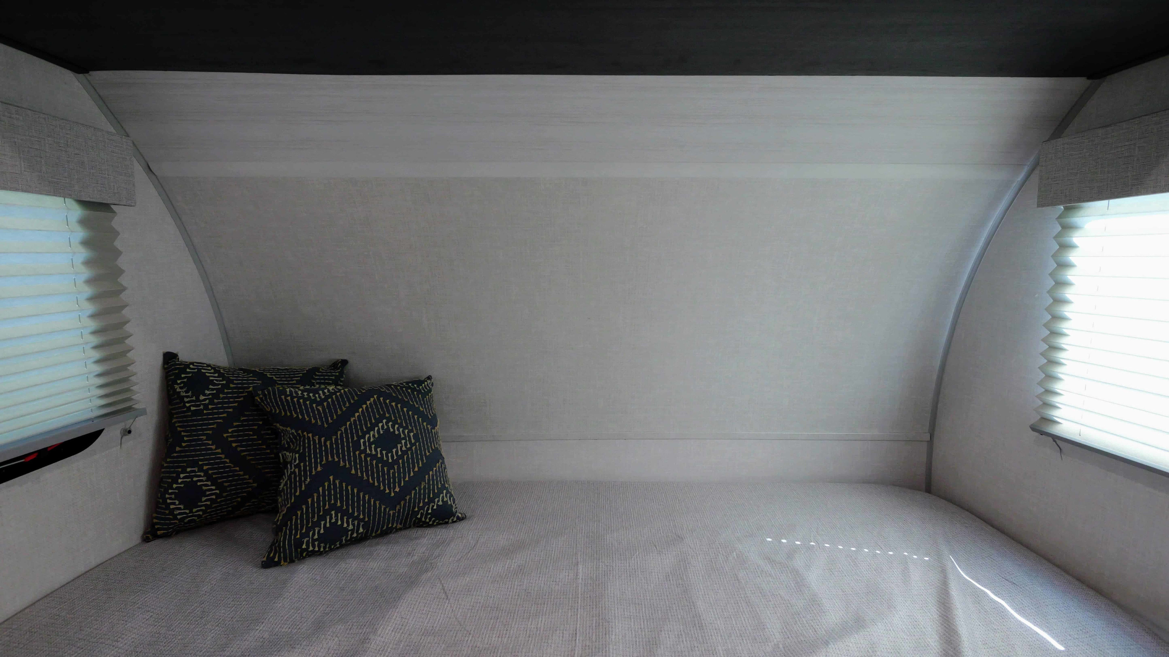 Cozy rv rental bedroom interior, featuring a compact bed with pillows and windows on either side.. Forest River R-Pod 190 2024