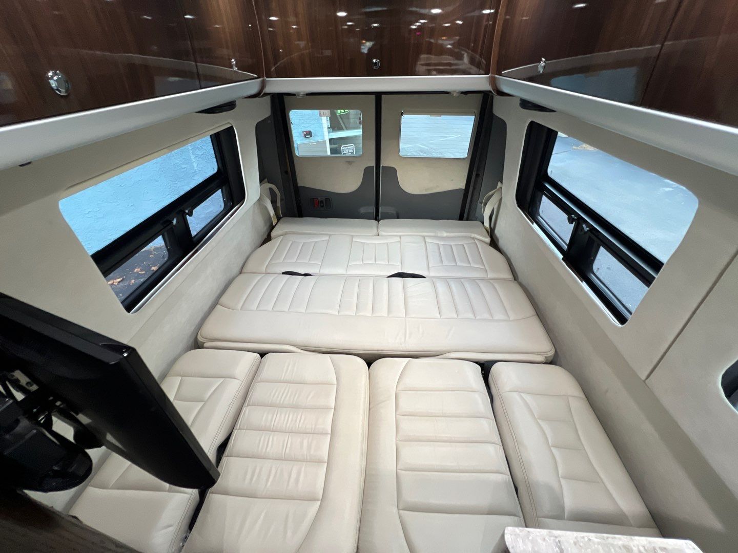 Spacious RV rental interior with convertible cream seating/bedding, wood cabinets, and large side windows for a comfortable camper van experience.. Airstream Interstate 2016