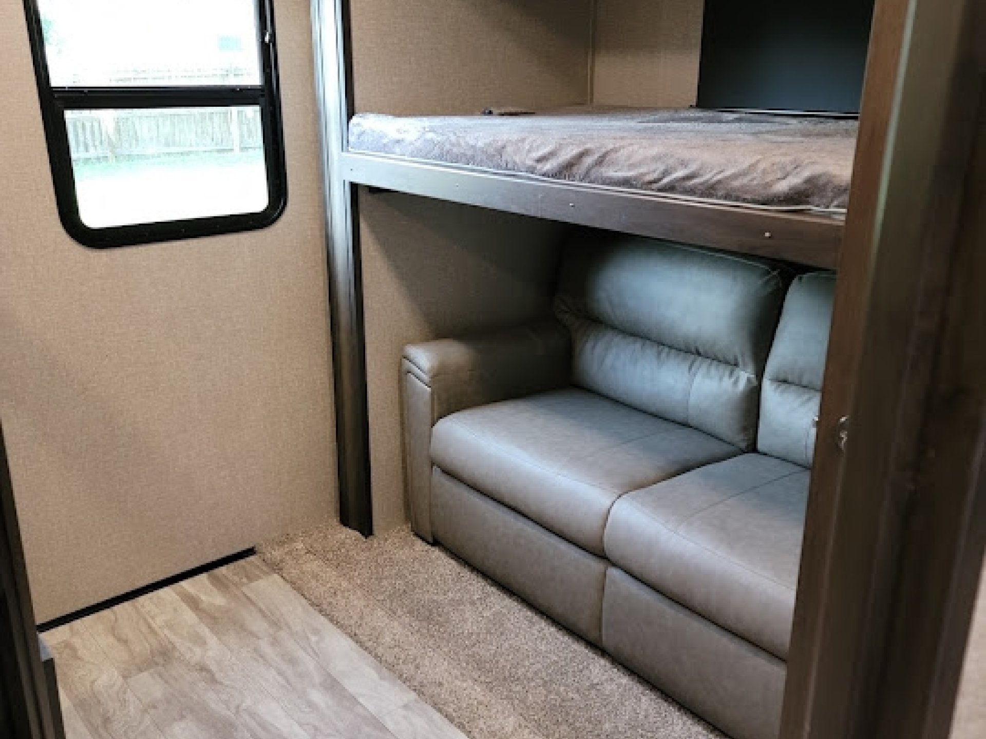 RV rental: Cozy interior with bunk bed over a sofa, window, and wood-look floor transitions to carpet.. Grand Design Reflection 2020