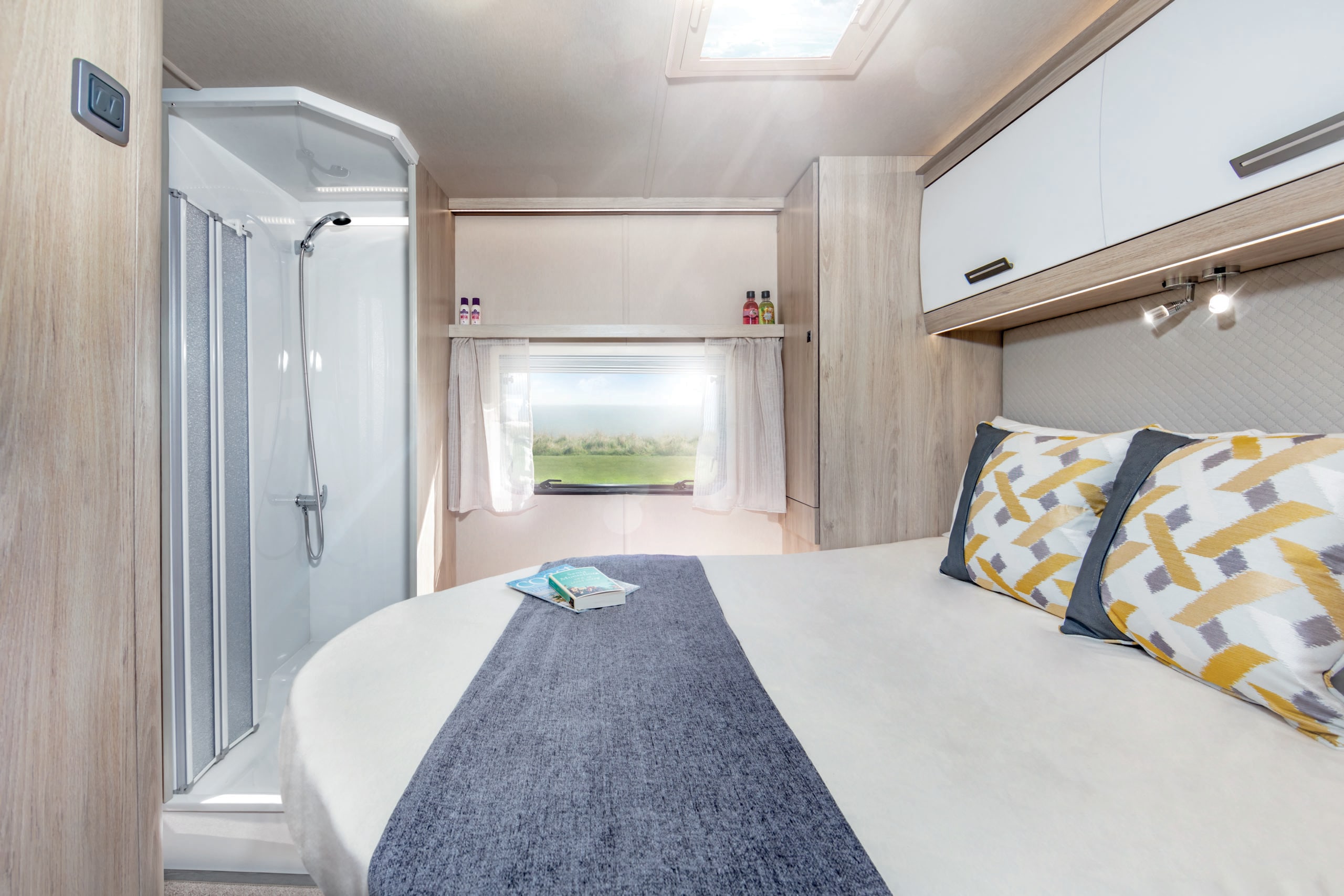 Modern rv rental bedroom featuring a cozy bed, compact shower, and window with a scenic view, ideal for comfortable travel.. Ford Autotrail F74 2022