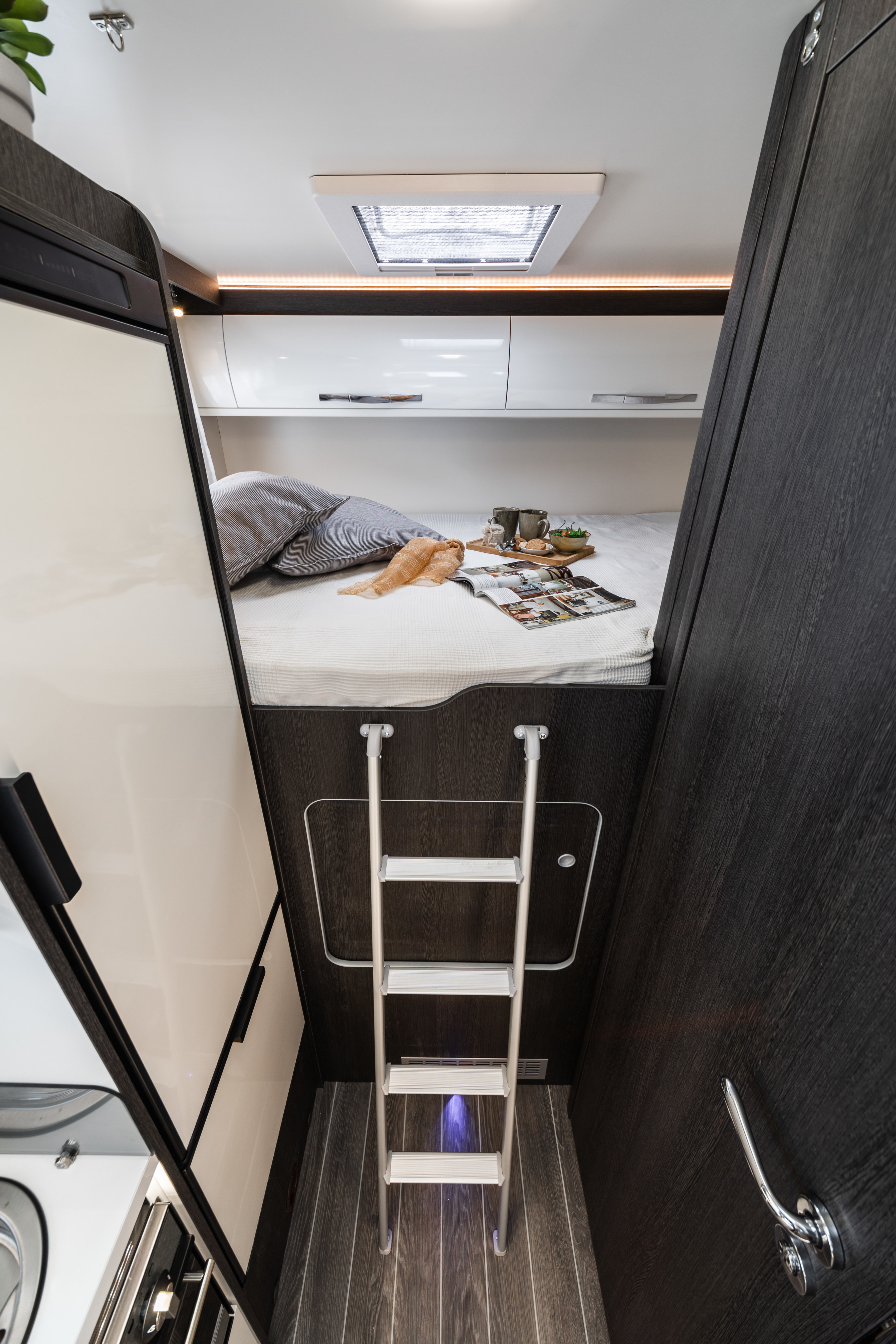 Explore this RV rental's clever design: a comfortable bunk bed accessed by a ladder, with overhead storage & skylight.. Roller Team Zefrio 665 2021
