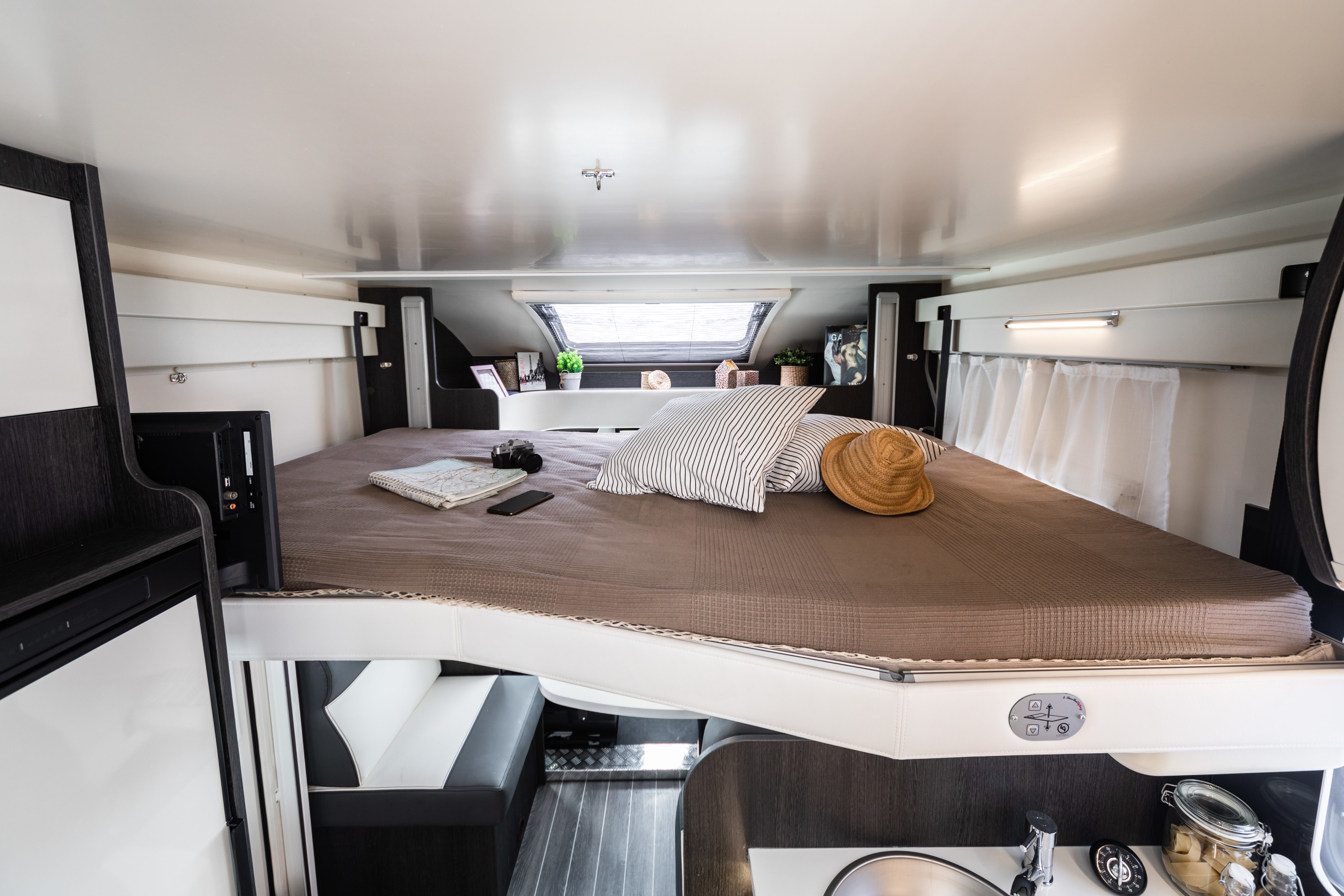 Inside a modern RV rental: elevated sleeping area, smart storage, and compact kitchen.. Rollerteam Zefiro 696 2018